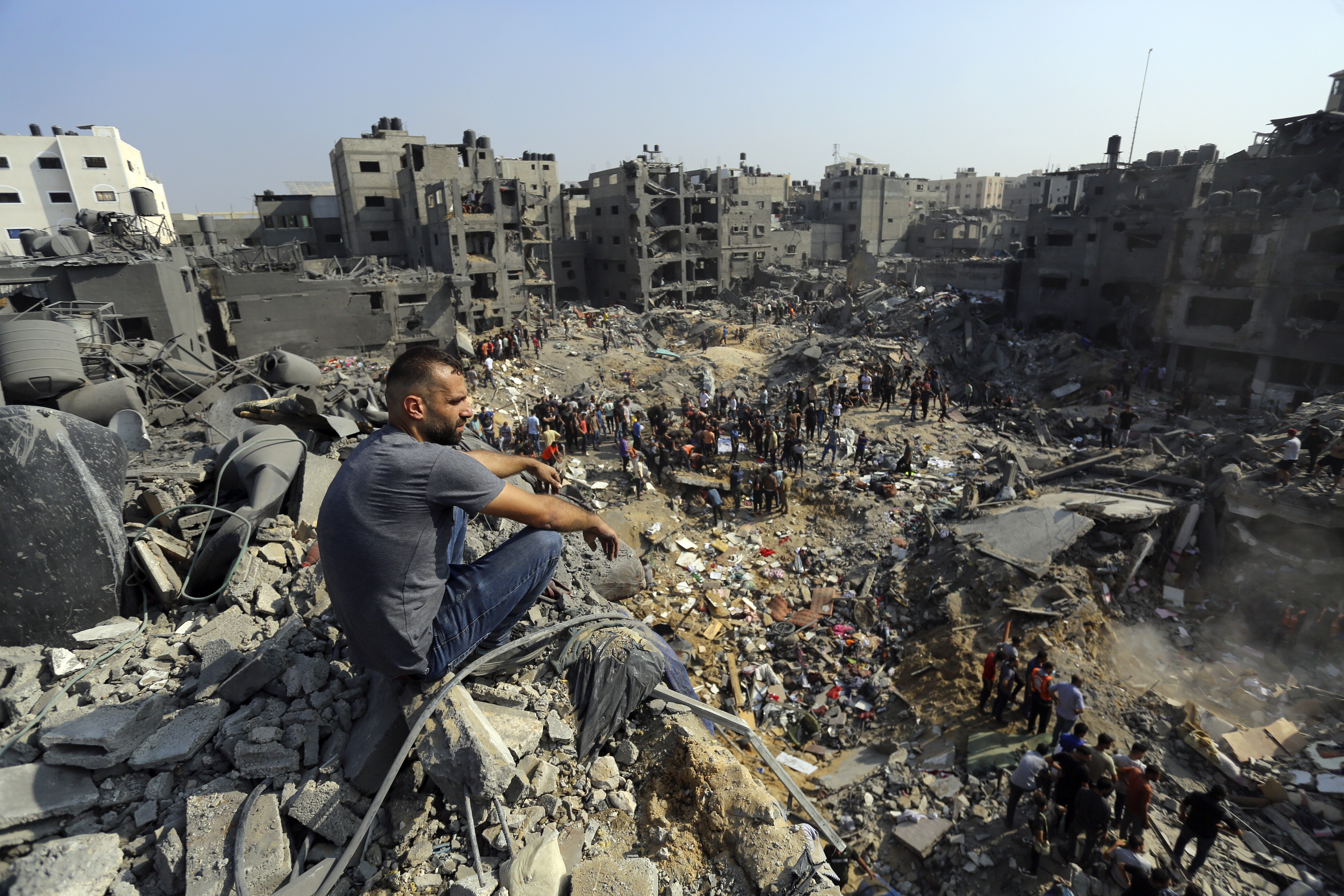 A man sits on the rubble as others wander among debris of buildings that were targeted by Israeli airstrikes in Jabaliya refugee camp, northern Gaza Strip, Wednesday, Nov. 1