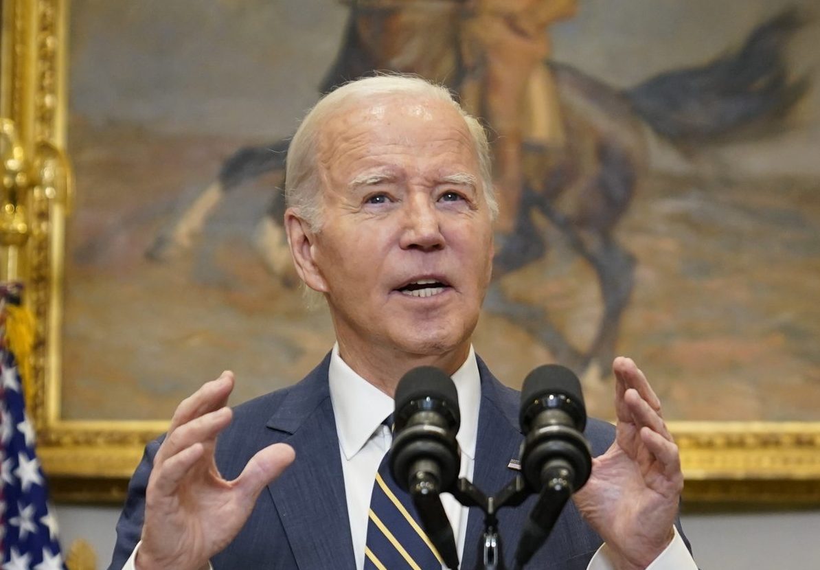 US President Joe Biden speaking from the Roosevelt Room. He is behind a lectern with flags behind him. He is making a point with his hands.