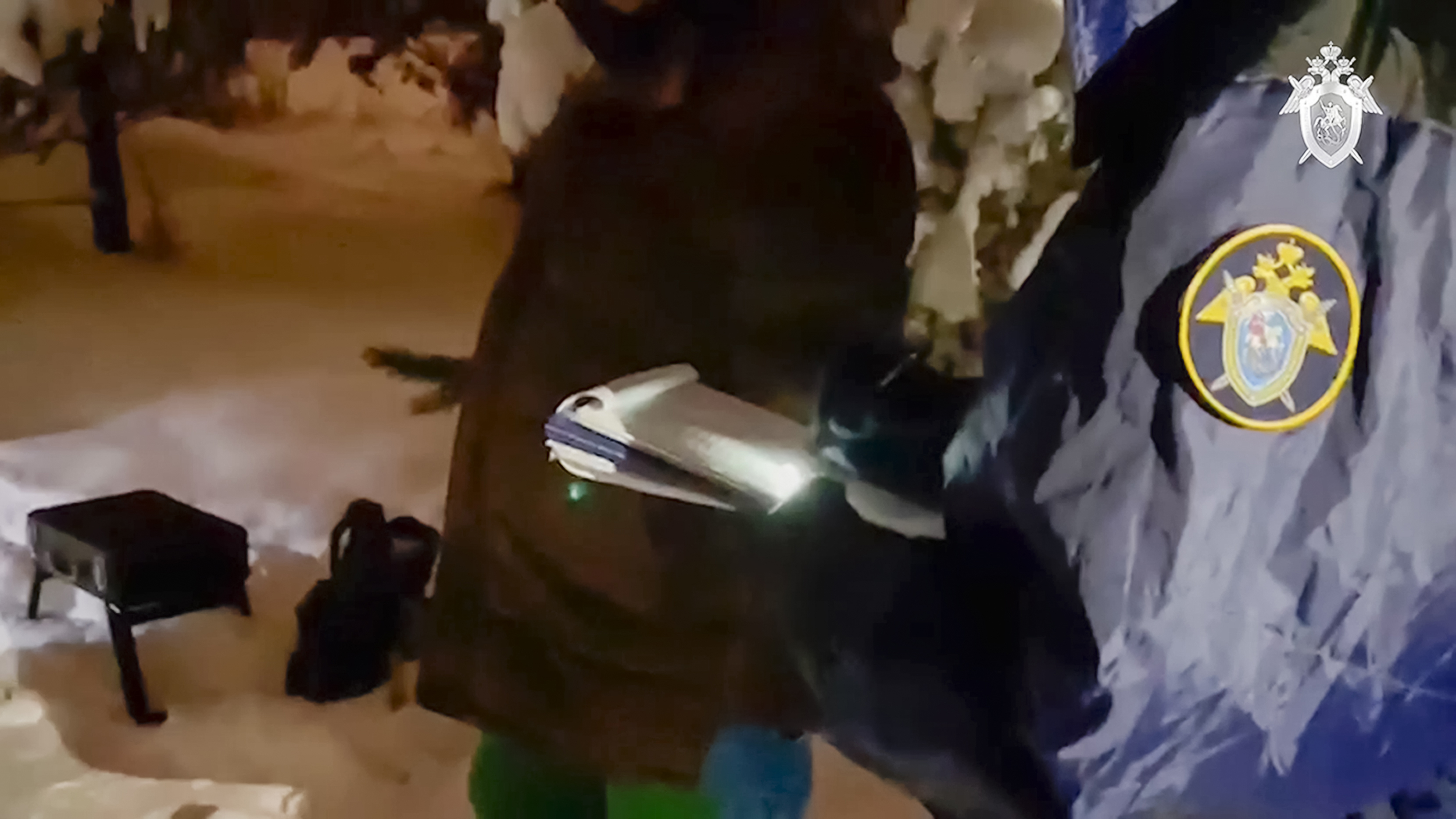 Investigators at the scene of Kyva's killing. The investigator has a note book. There is thick snow on the ground.