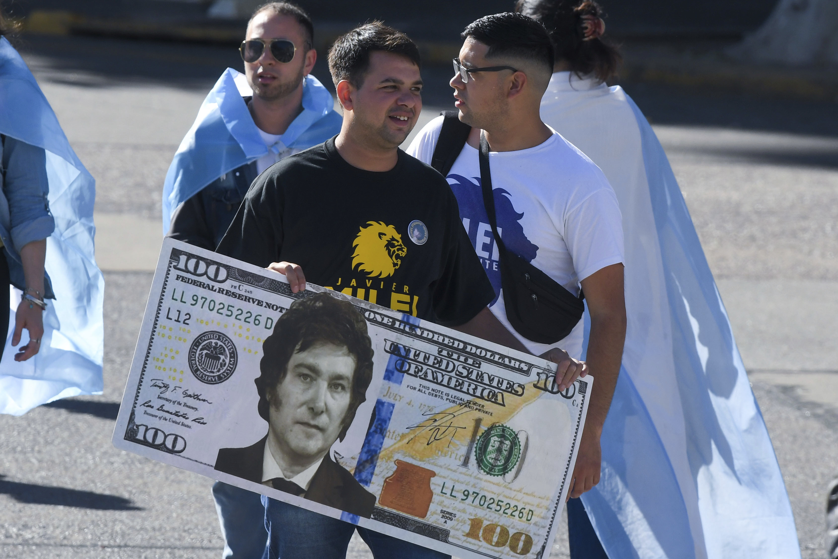 A supporter of Javier Milei carries a larger-than-life facsimile of a 100-dollar bill, with Milei's face in the centre.
