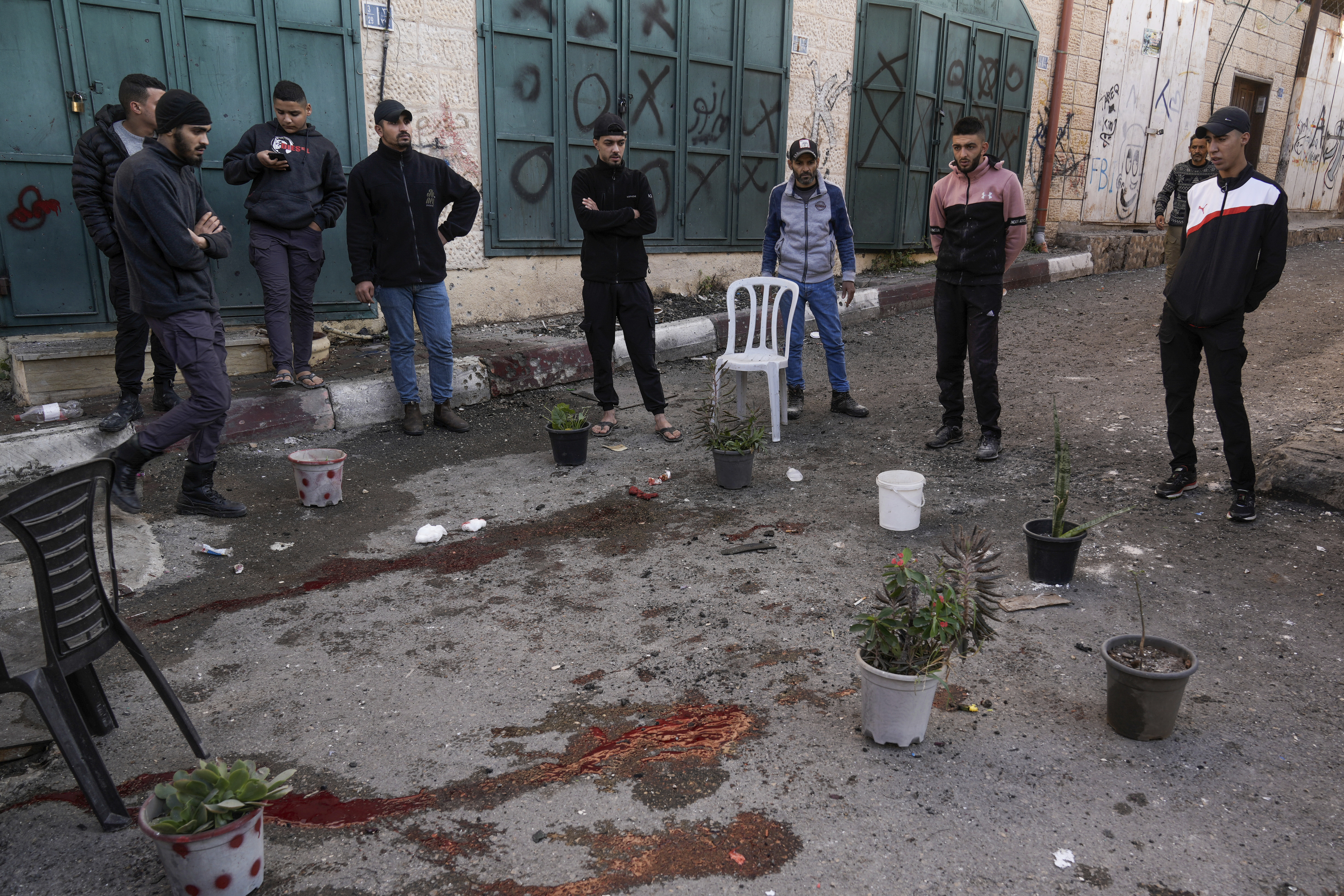 Palestinians look at a blood stain at the site of the Israeli army operation, in the Jenin refugee camp
