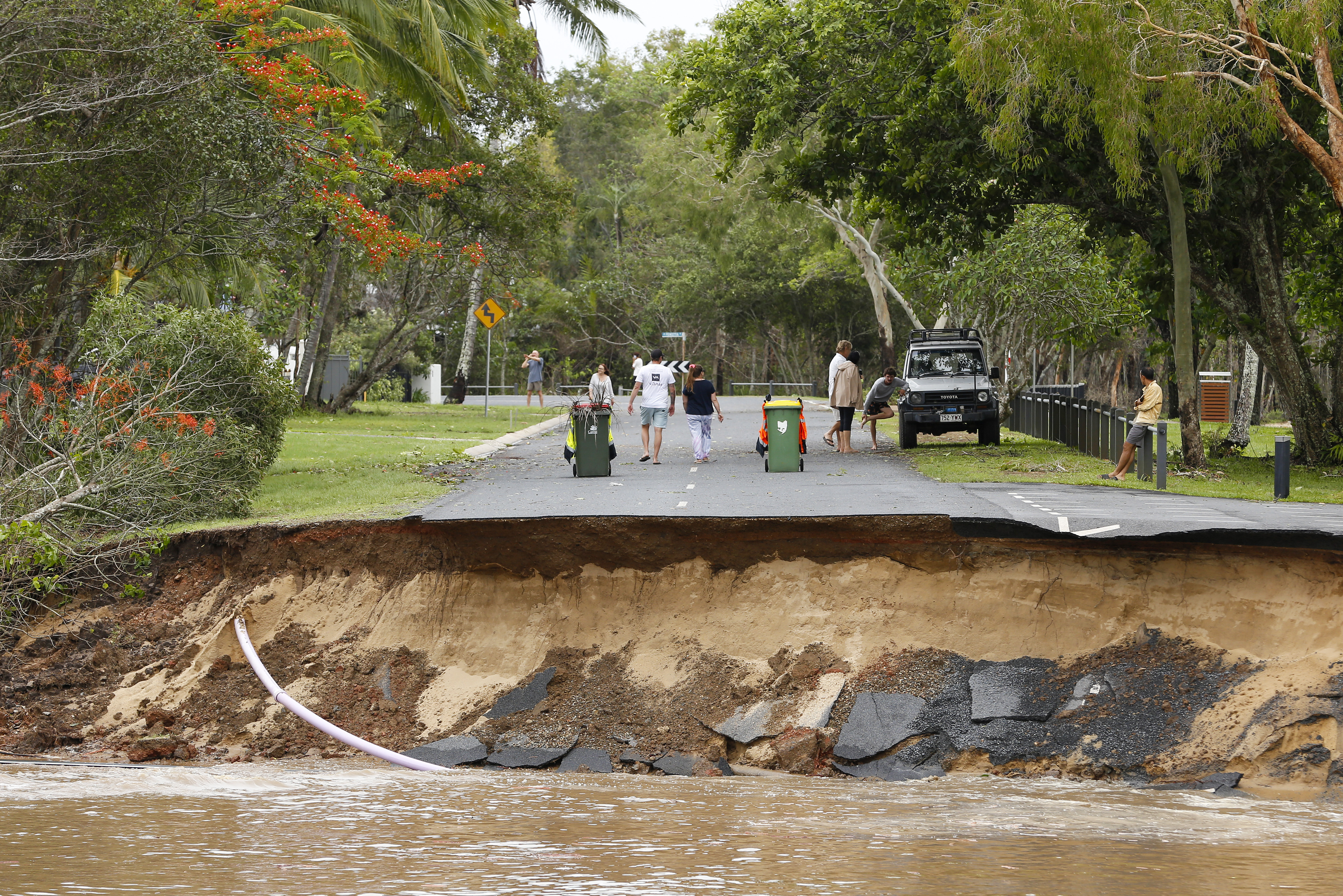 Stranded residents stand on a road, a large section of which has washed away, in the suburb of Holloways Beach in Cairns, Australia.