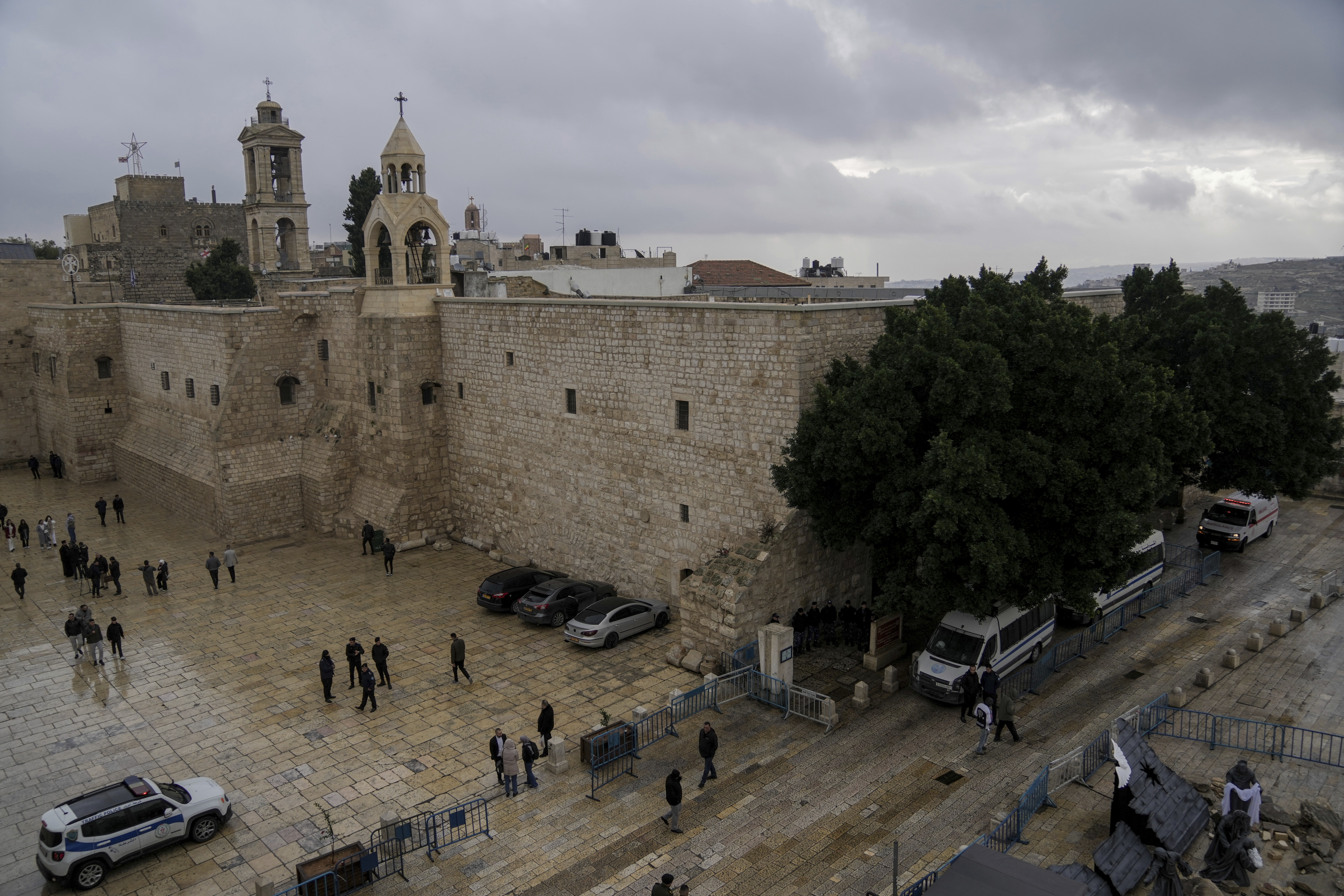 People walk by the Church of the Nativity, traditionally believed to be the birthplace of Jesus, on Christmas Eve, in the West Bank city of Bethlehem, Sunday, Dec. 24