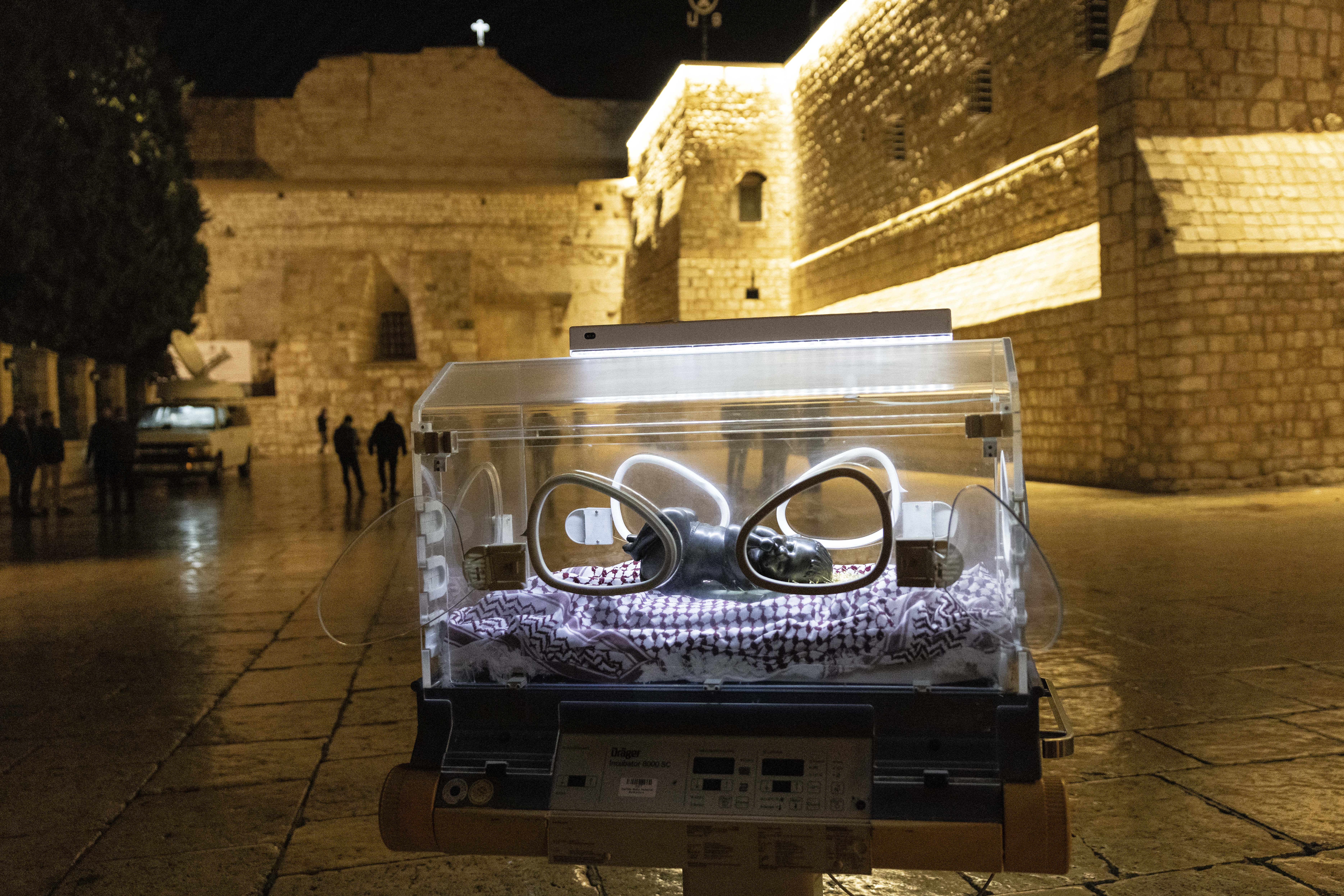 a bronze statue inside an illuminated incubator outside a stone church