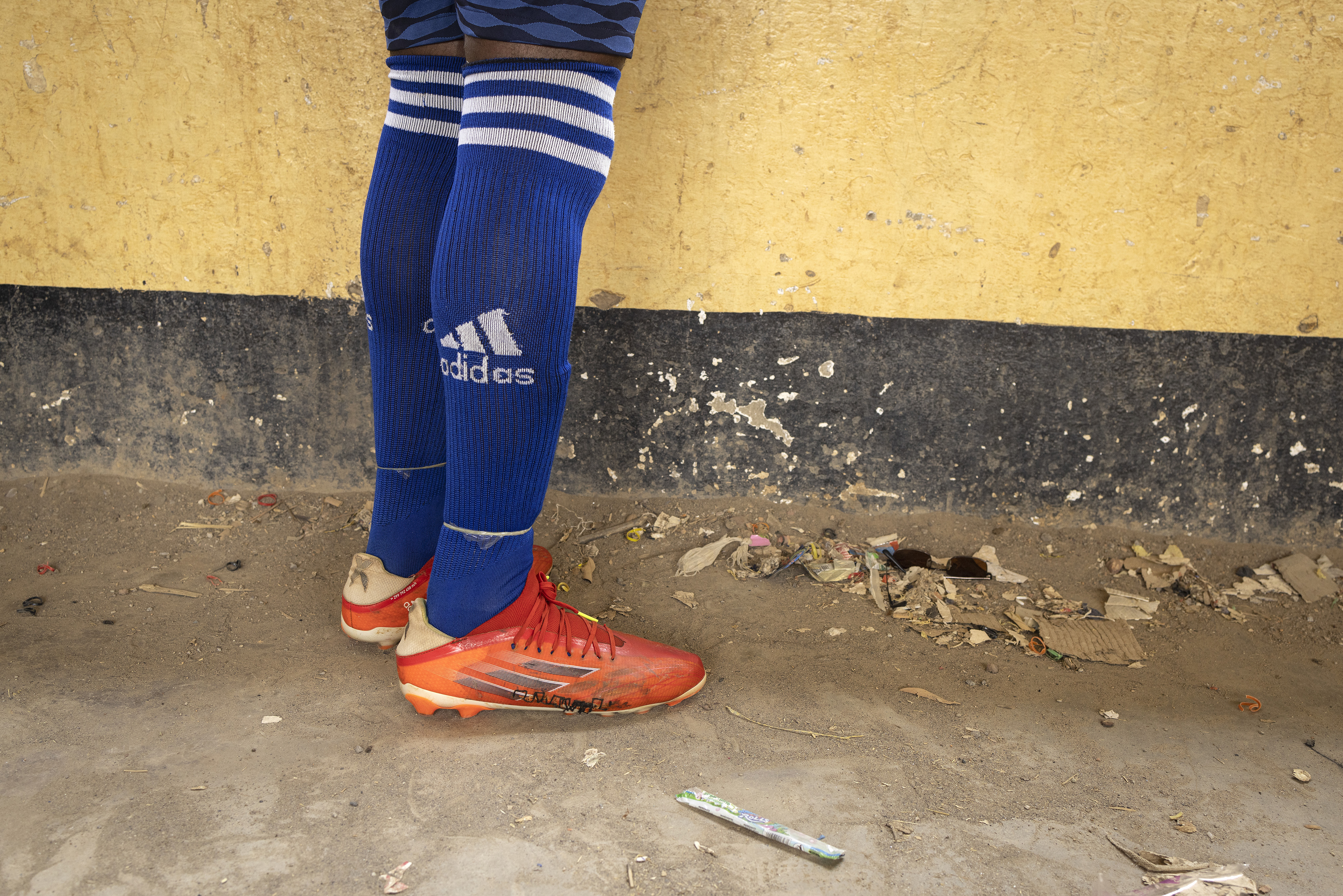 A football player wearing worn-out boots that have been patched together