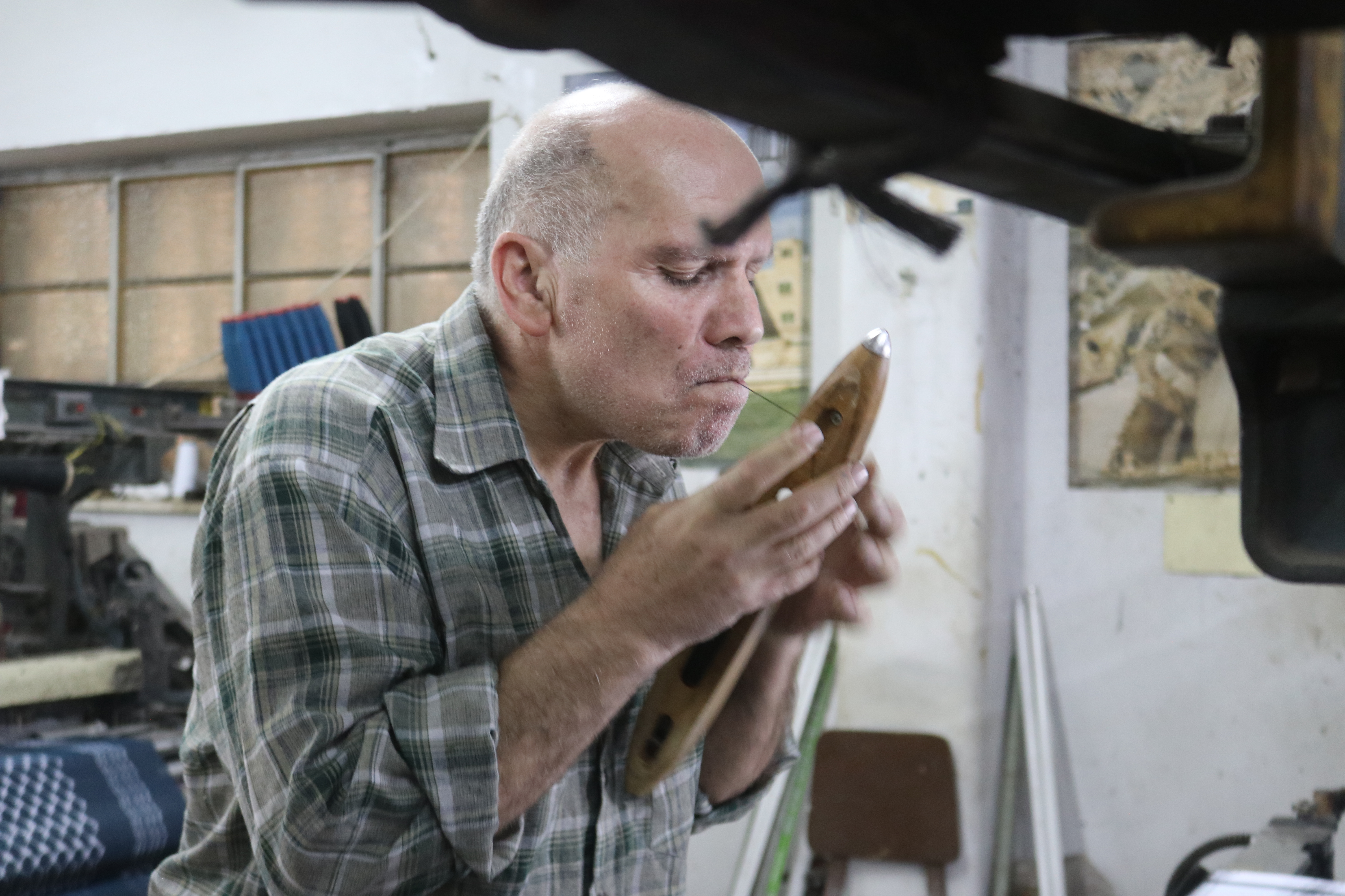 Ezzaat Al-Harbawi inspects one of the shuttles used in making the keffiyeh, 