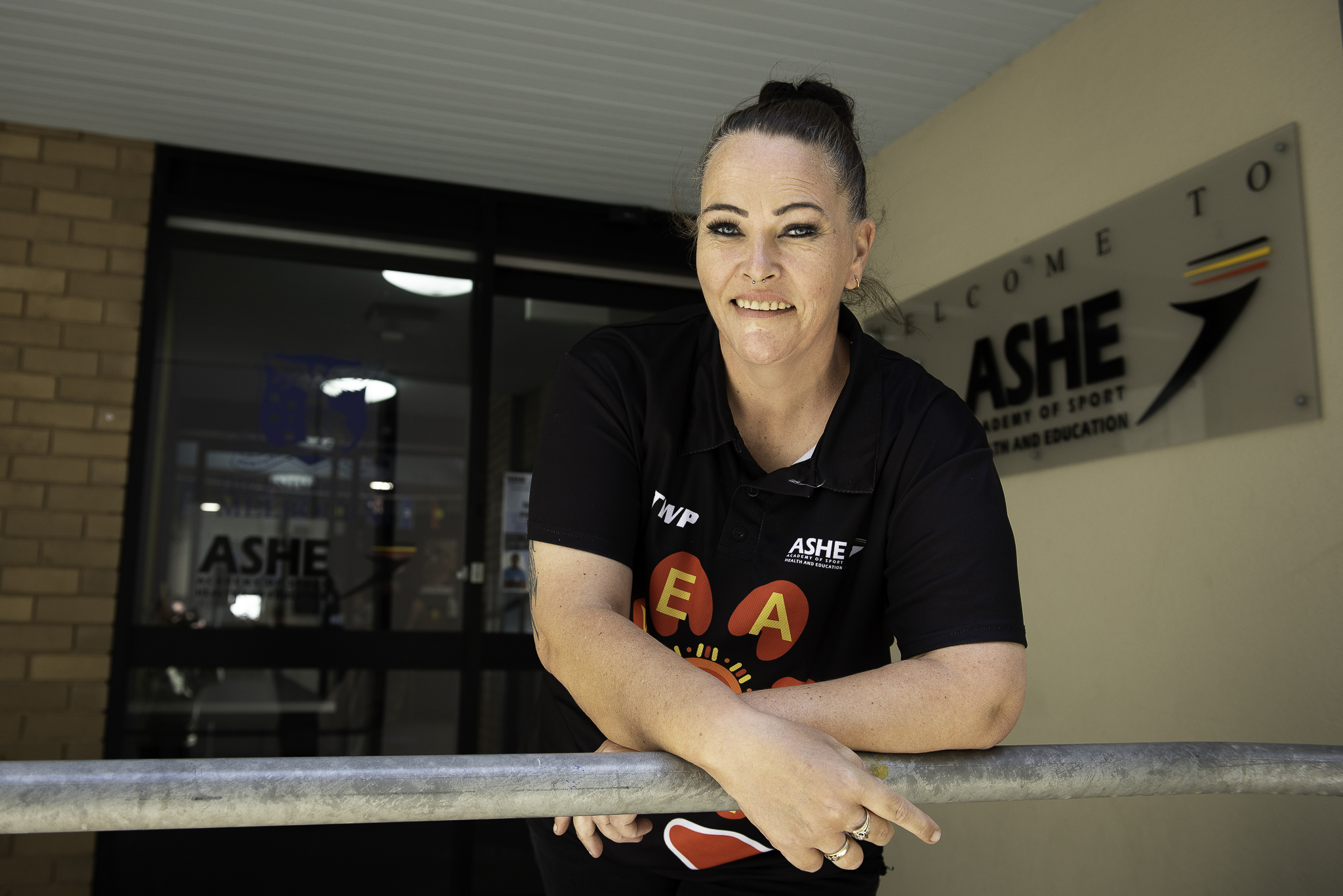 Heidi Knowles outside the Academy of Sport, Health and Education (ASHE). She is wearing a t-shirt. She looks happy and relaxed.