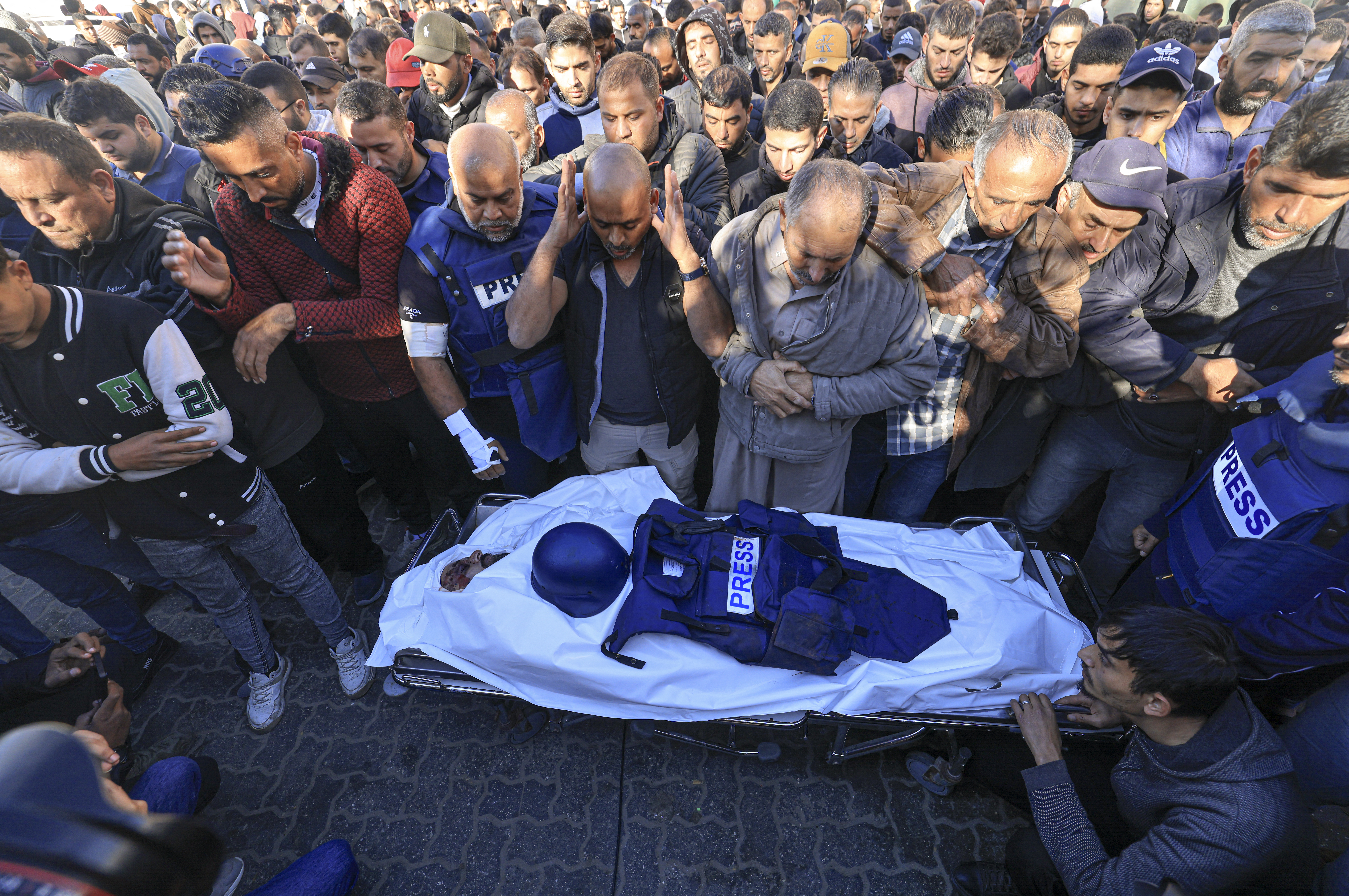 Colleagues and family members pray over the body of Al Jazeera cameraman Samer Abudaqa, who was killed during Israeli bombardment, during his funeral in Khan Yunis on the southern Gaza Strip on December 16, 2023. [Mahmud HAMS / AFP]