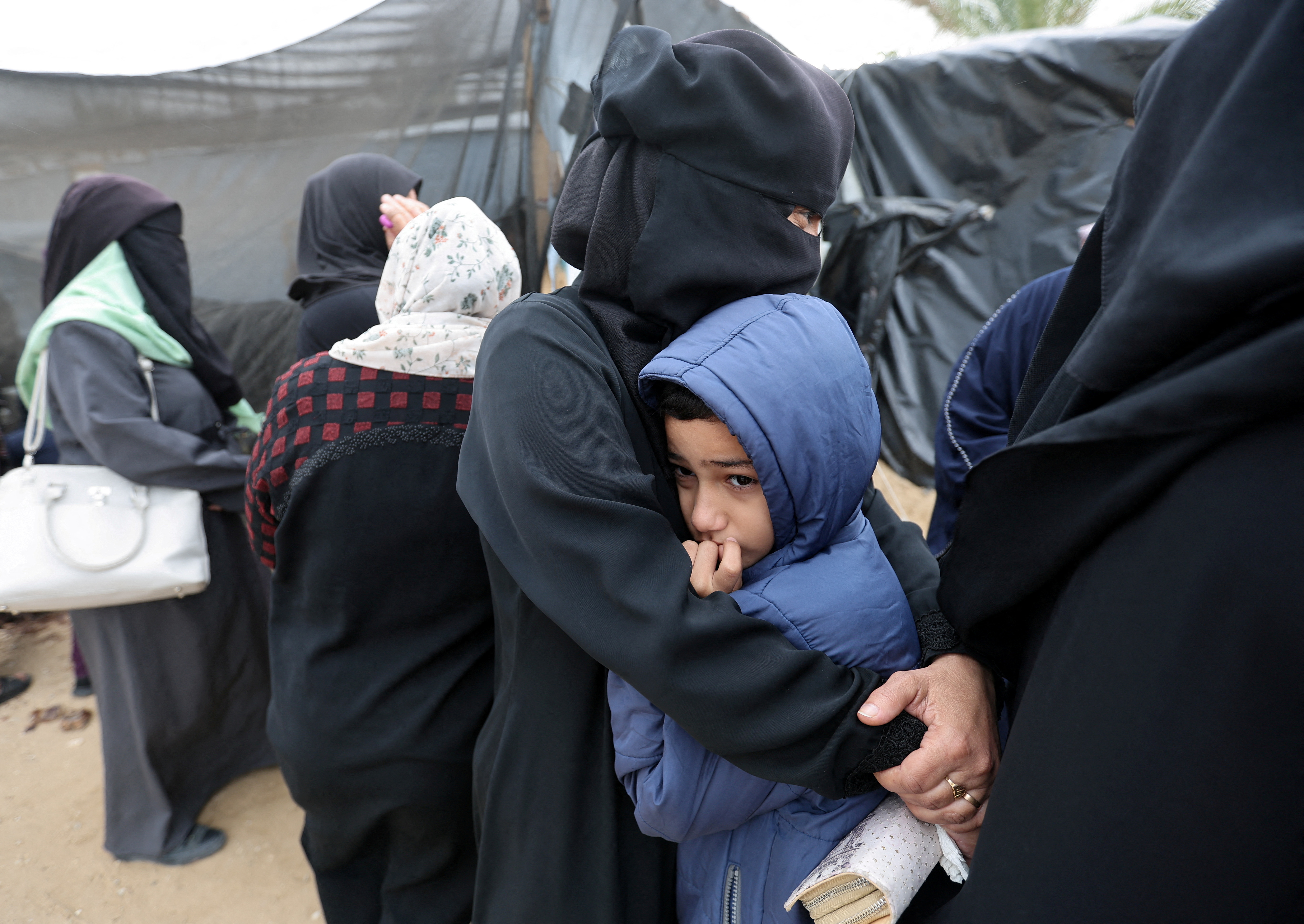 A woman embraces a child as Palestinians wait to receive flour bags distributed by the United Nations Relief and Works Agency (UNRWA) during a temporary truce between Hamas and Israel, in Khan Younis in the southern Gaza Strip November 27, 2023. REUTERS/Ibraheem Abu Mustafa TPX IMAGES OF THE DAY