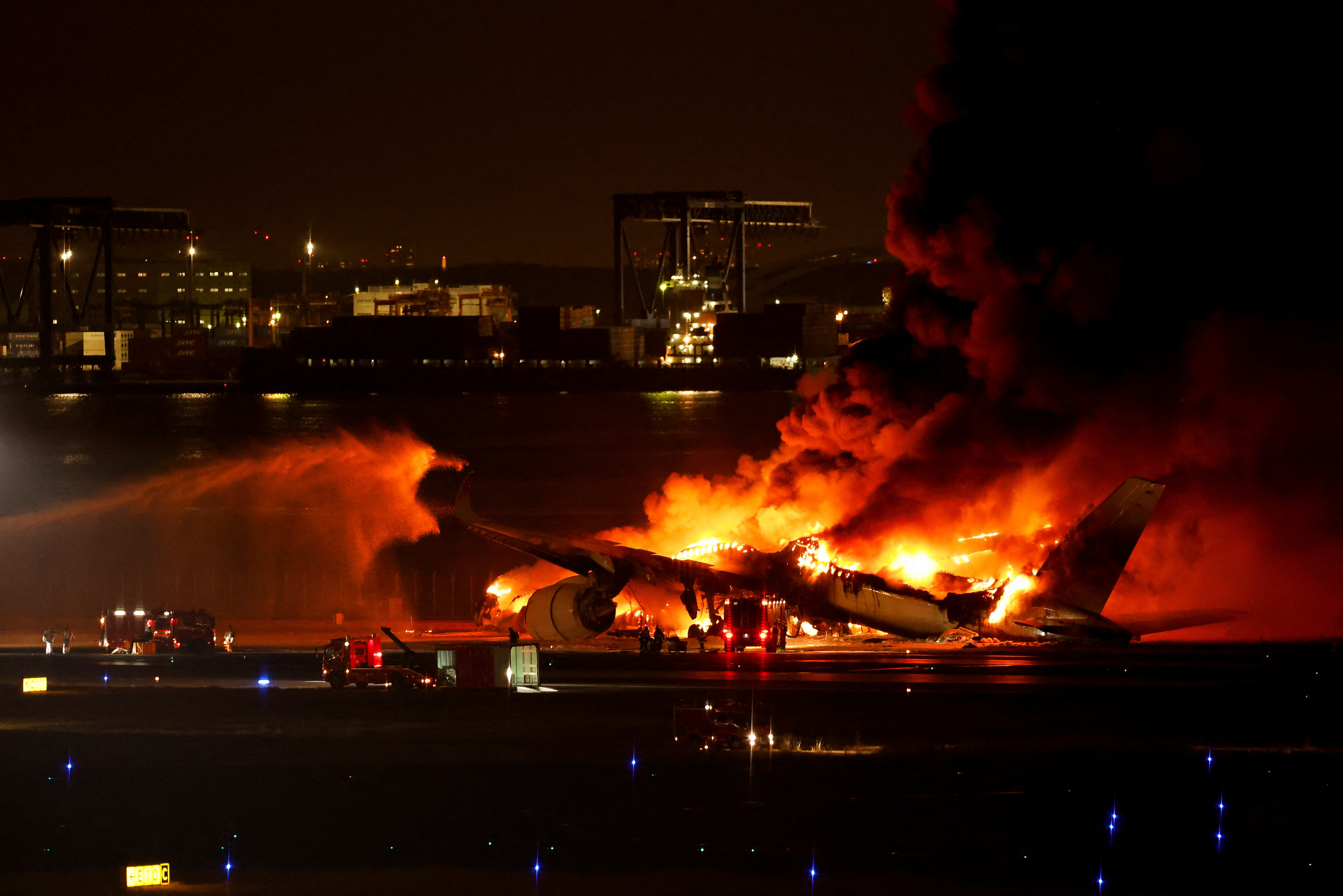 Firefighters work at Haneda International Airport after Japan Airlines' A350 airplane caught on fire, in Tokyo, Japan