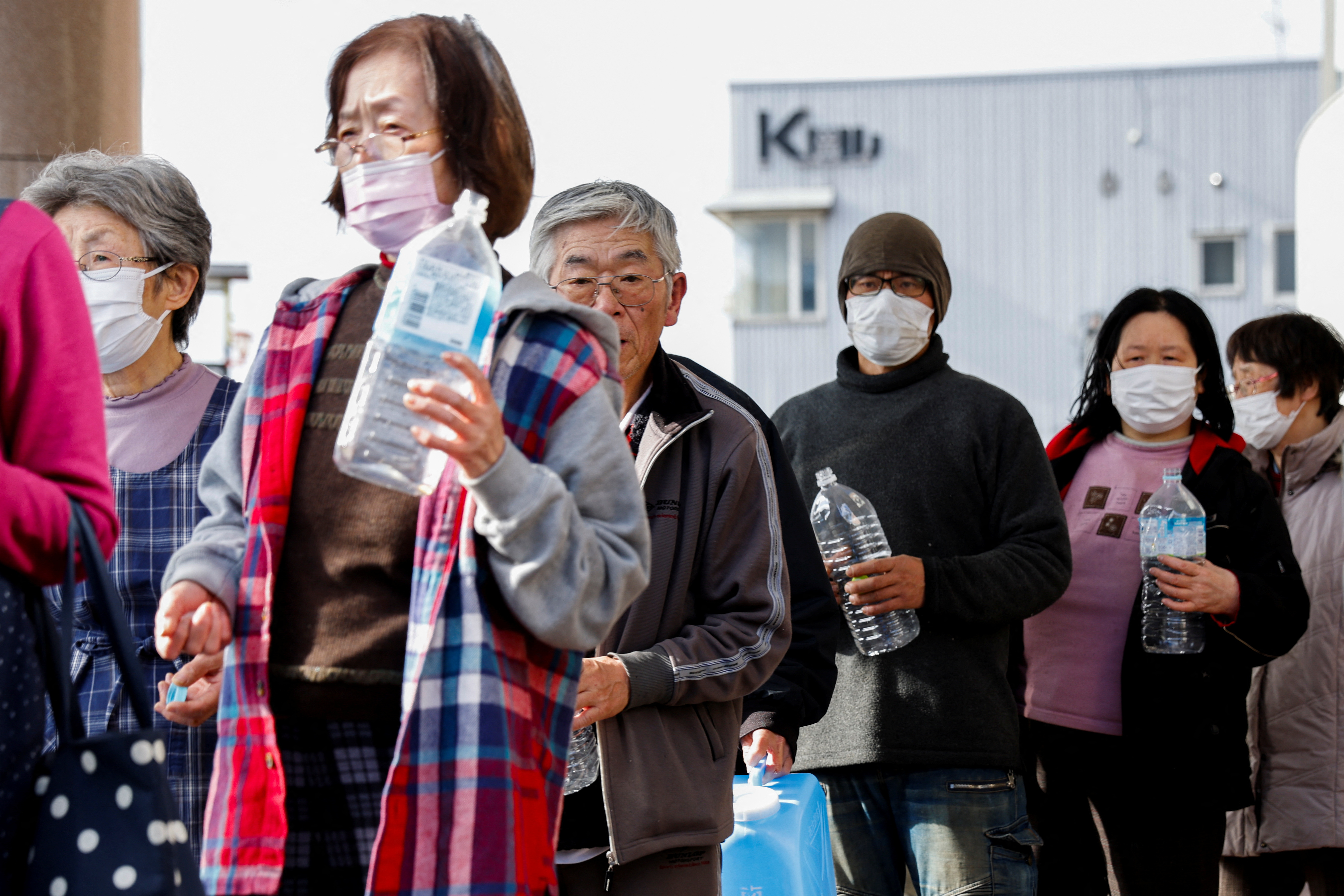 People queue for water in Wajima. They're holding small plastic bottles