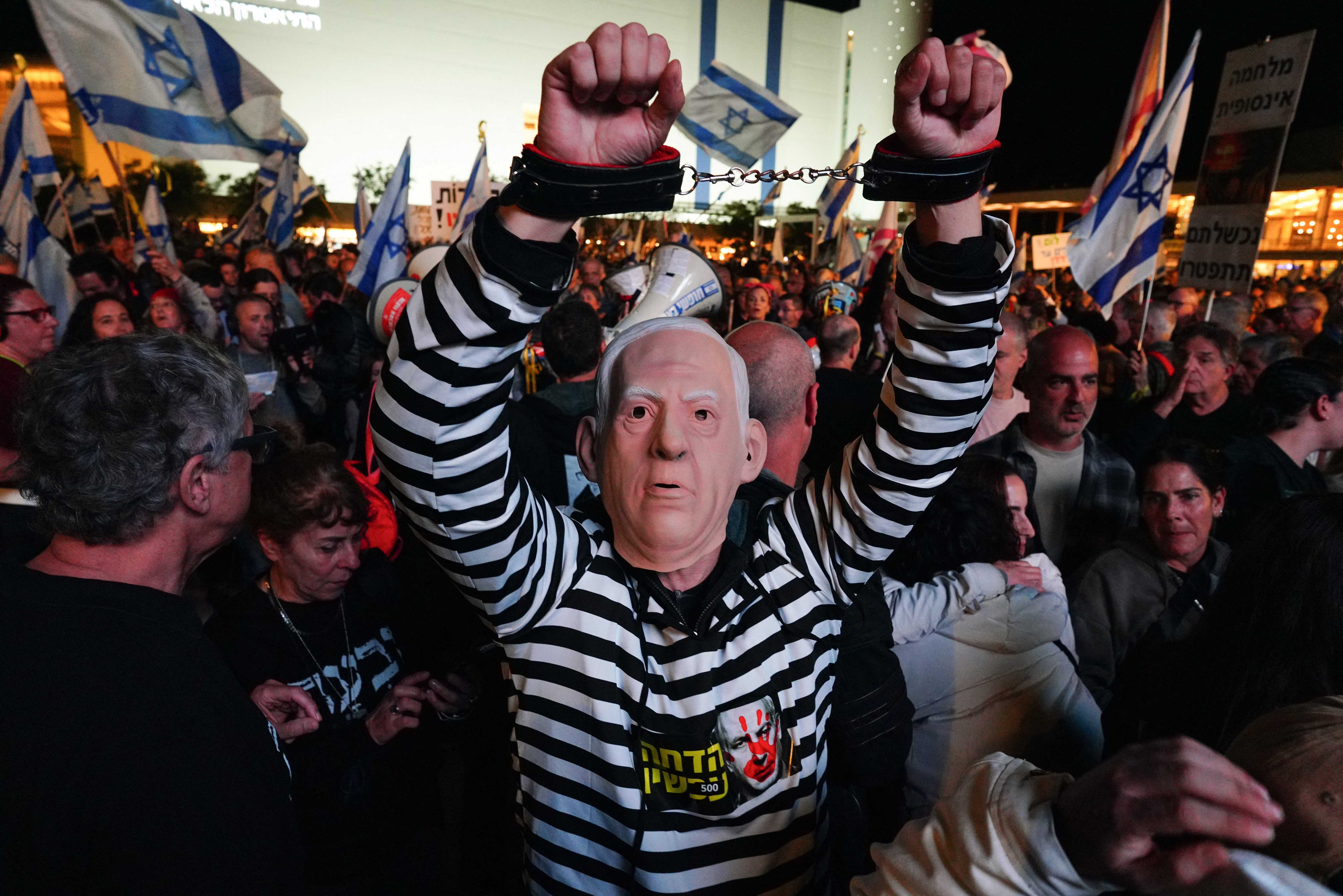 A person in prison clothes wears a mask depicting Israeli Prime Minister Benjamin Netanyahu during a demonstration against Netanyahu's government in Tel Aviv, Israel, January 6