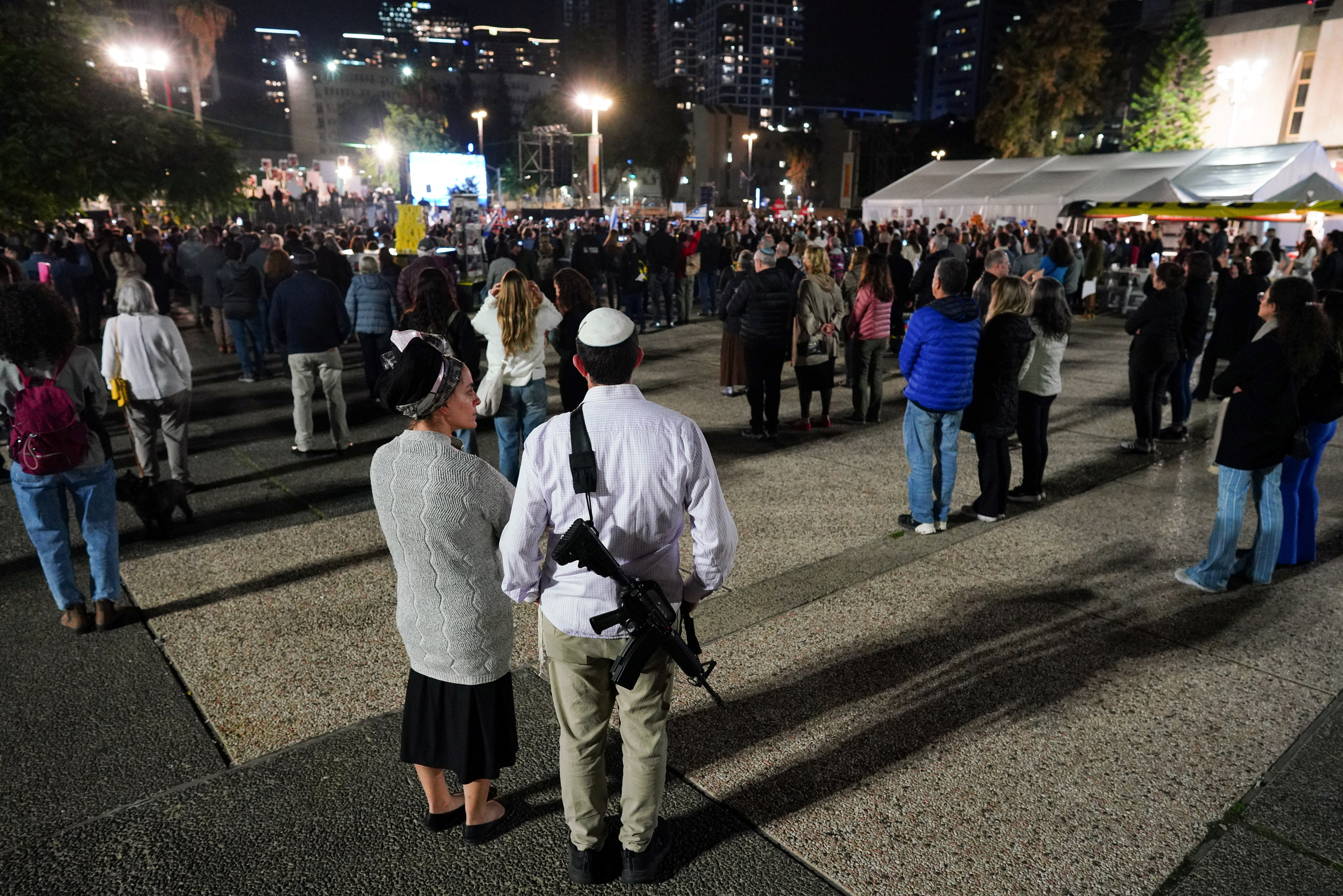 A man carries a weapon as families of hostages and supporters protest to call for the release of hostages kidnapped on the deadly October 7 attack by Palestinian Islamist group Hamas, in Tel Aviv, Israel