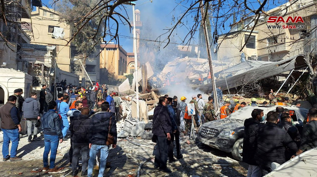 People inspect the damage at the site of the strike in Damascus