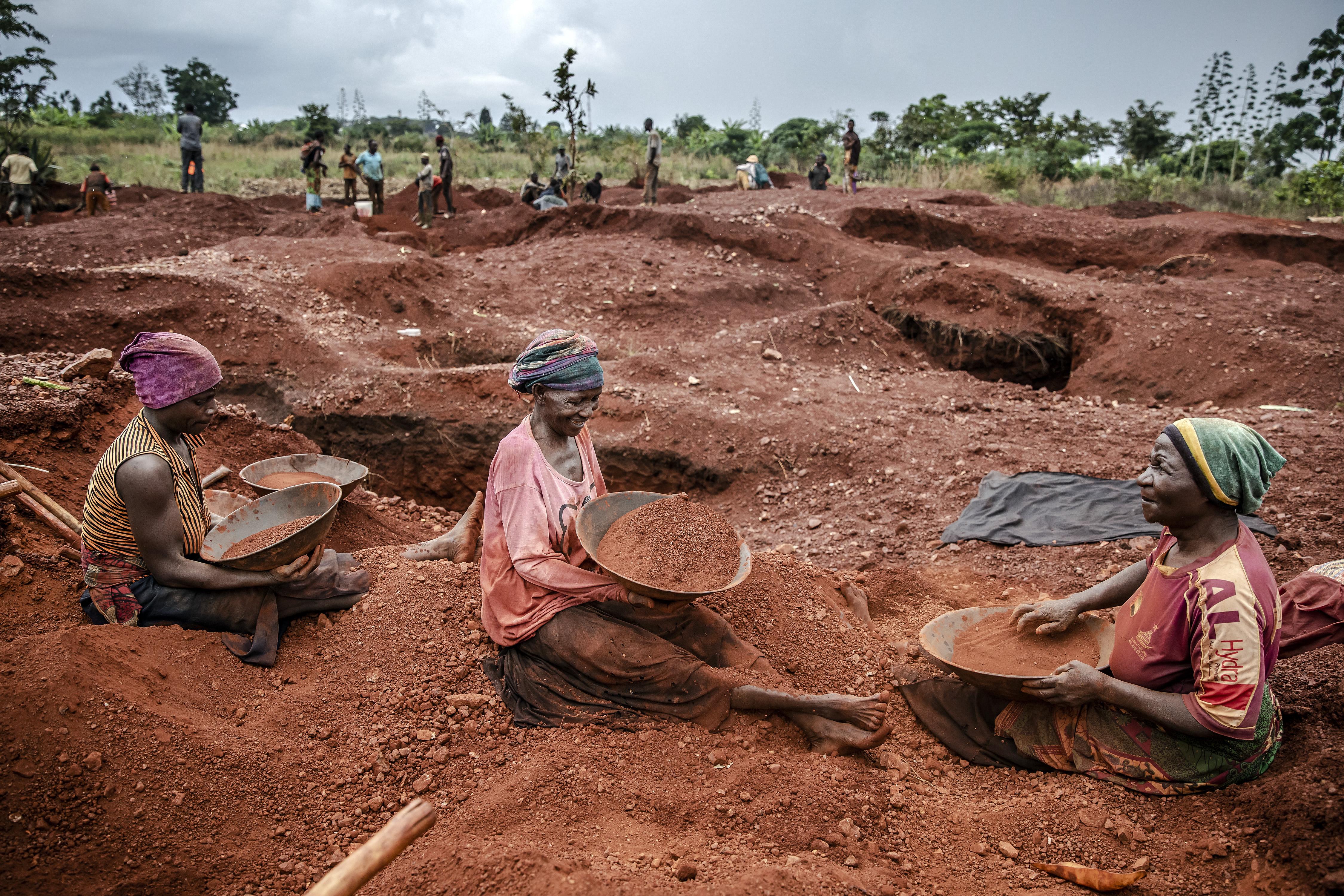 Tanzanian miners Mwagyma Ramadhan, Regina Daud and Maria Ng'ombe look for gold at an open-pit gold mine in Nyarugusu, Geita Region, Tanzania on May 27, 2022. Tanzania is a land rich in minerals and one of the main gold producers in Africa, with gold representing more than 90% of the country's mineral exports. Artisanal and small-scale gold mining have culturally and historically relegated women's participation. The extractive sector in Tanzania has historically been a male-dominated industry with high levels of harassment, sexual abuse, discrimination and misconceptions over women's involvement, and contributions following traditional beliefs. A a result women face economic challenges due to lack of access to the land. Through the creation only-women miners associations and the help of projects advocating for rights and inclusion in the extractive industry such as the Collective Action For Rights Realisation In Extractives Industry (CLARITY), Tanzanian women in Geita region have been gradually gaining access to the mines while being able to benefit from the sector. (Photo by LUIS TATO / AFP)
