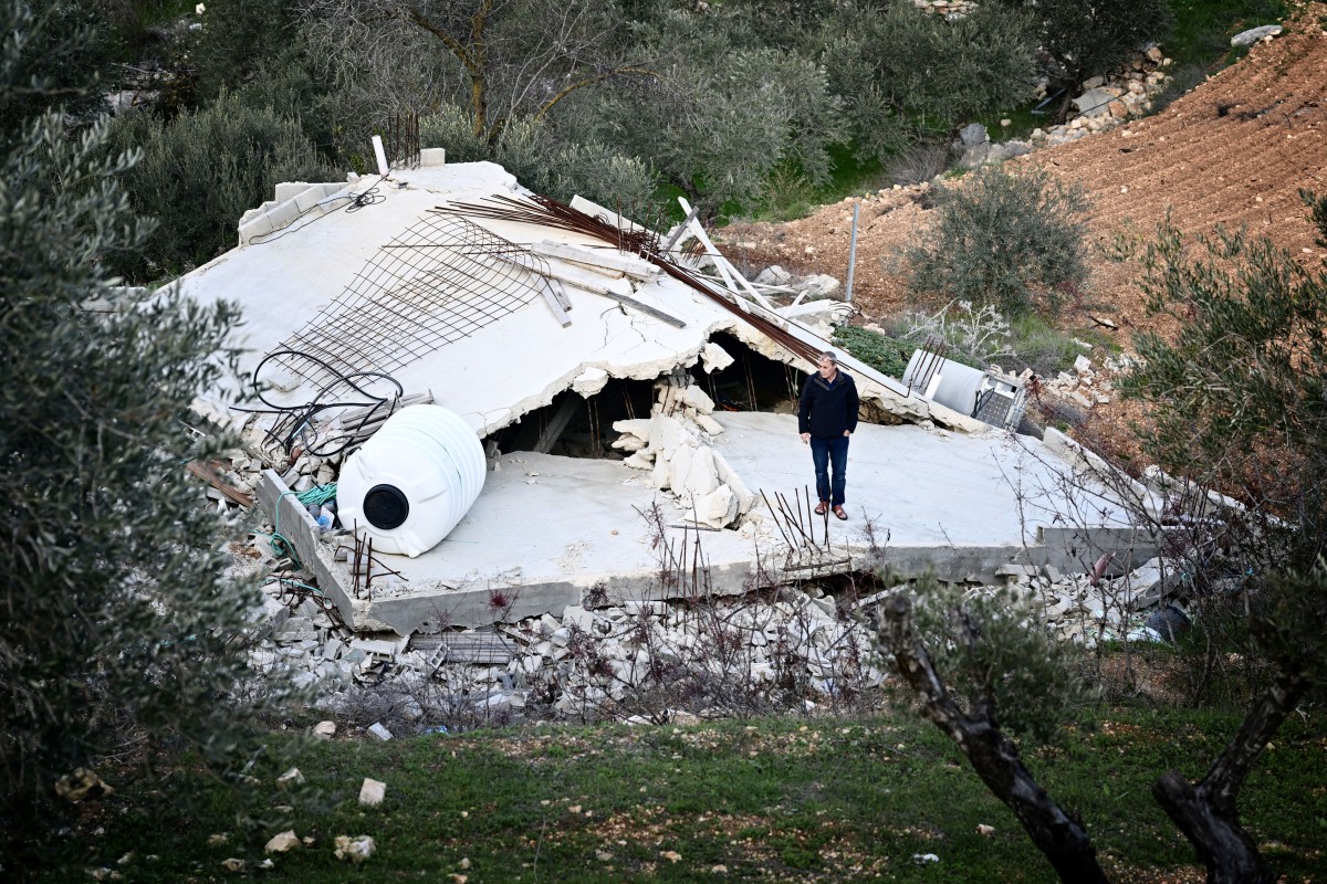 Palestinian villager Waji al-Atrash poses in front of his bulldozed house