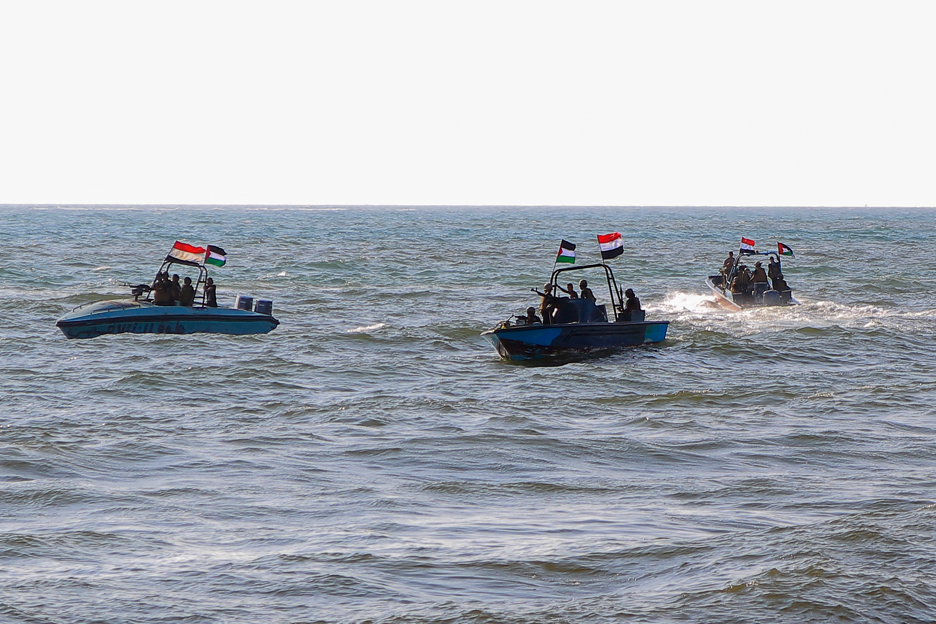 people on boats wave Yemeni and palestinian flags