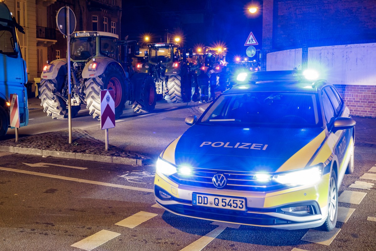 A police car stands next to a farmers' protest parading on their tractors during demonstrations against the federal government's austerity plans in Torgau, eastern Germany,