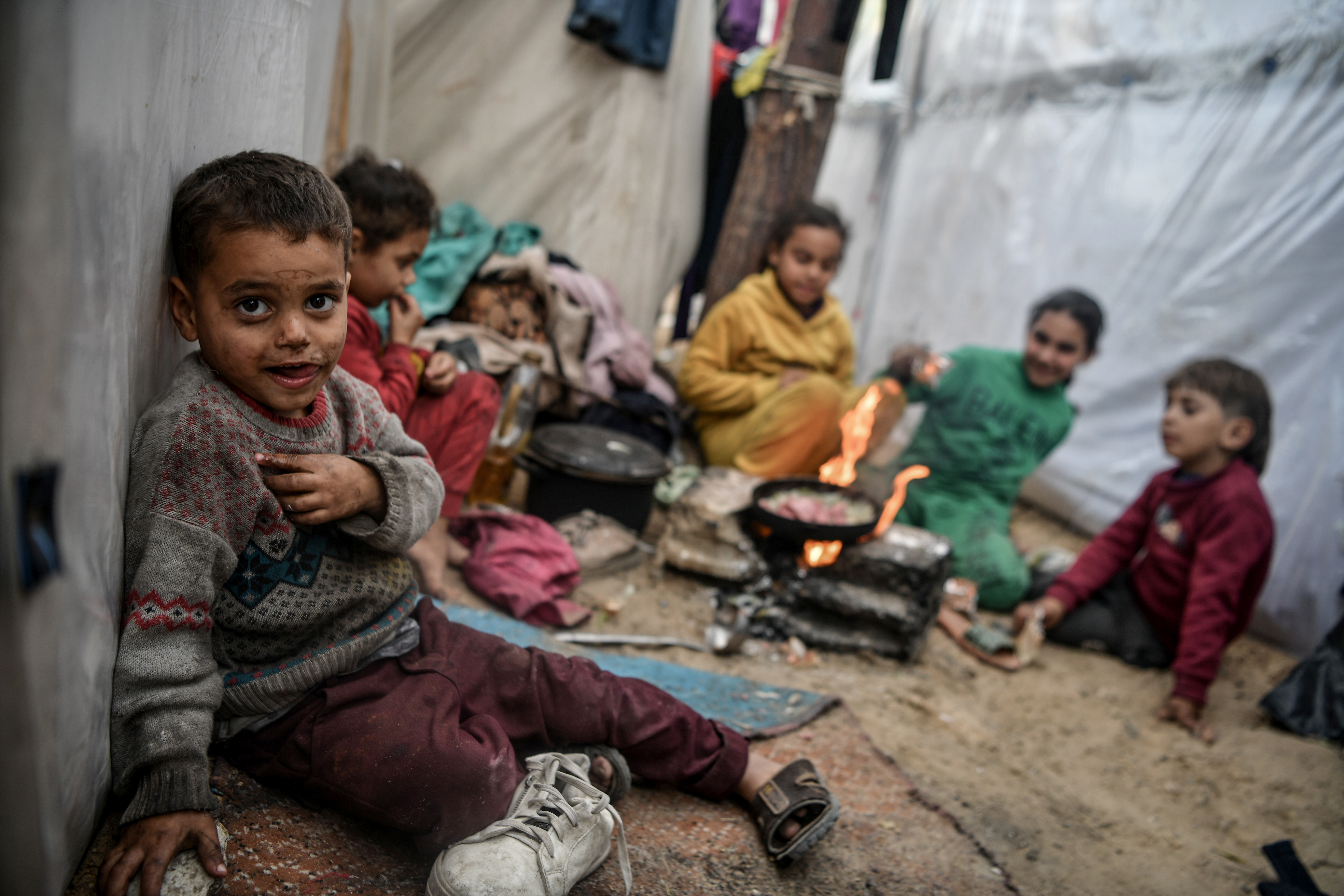 Palestinian children cook a meal among tents for displaced people while Israel's attacks on Gaza continue [Abed Zagout/Anadolu Agency]