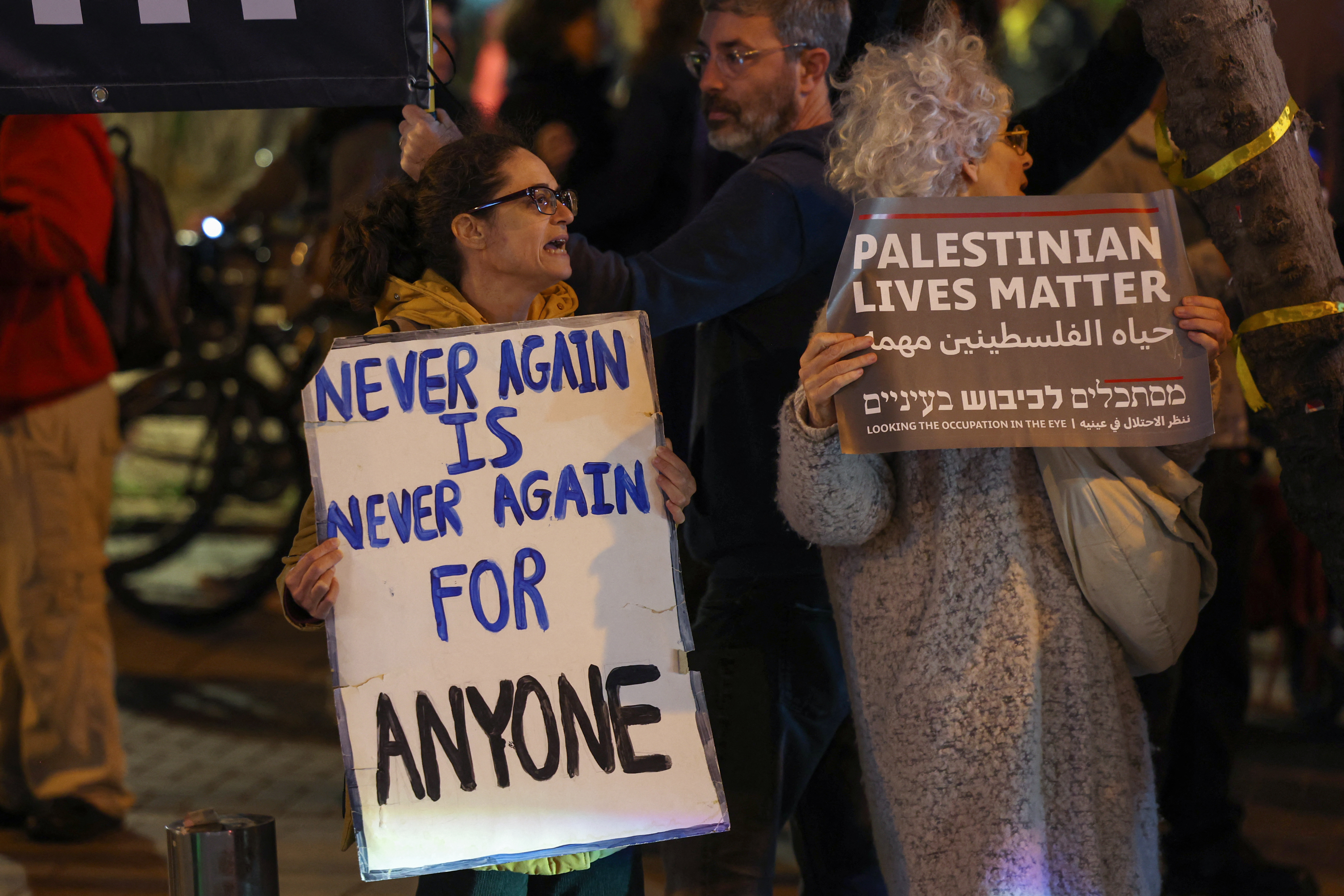 Israeli left-wing activists lift placards during a protest against the war in Gaza outside the Ministry of Defence in the central city of Tel Aviv