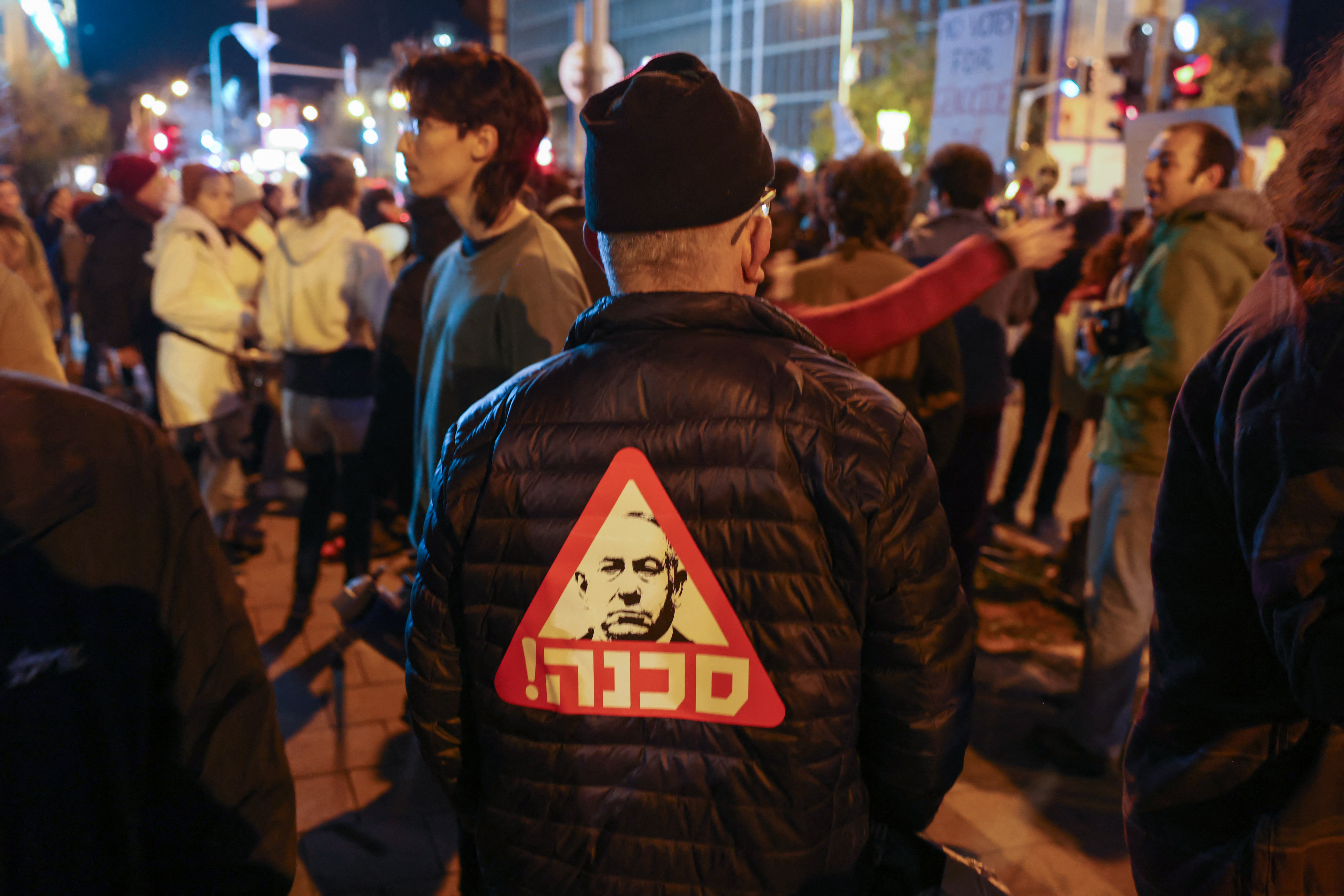 A protester wears a garment bearing a portrait of Israeli Premier Benjamin Netanyahu with a Hebrew inscription which reads "dangerous" as left-wing activists rally against the war in Gaza outside the Ministry of Defence in the central city of Tel Aviv on January 27
