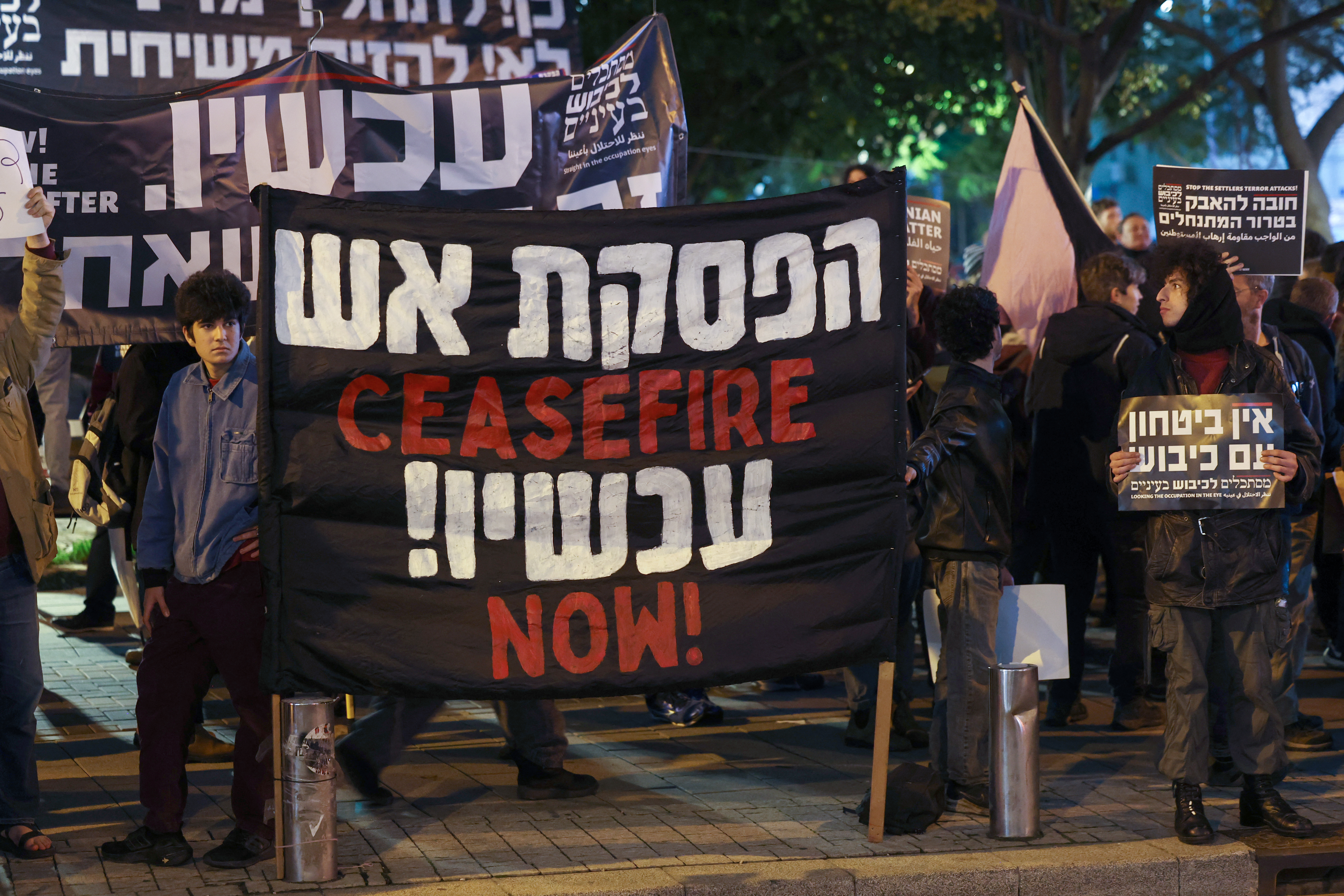 Israeli left-wing activists lift placards during a protest against the war in Gaza outside the Ministry of Defence in the central city of Tel Aviv on January 27