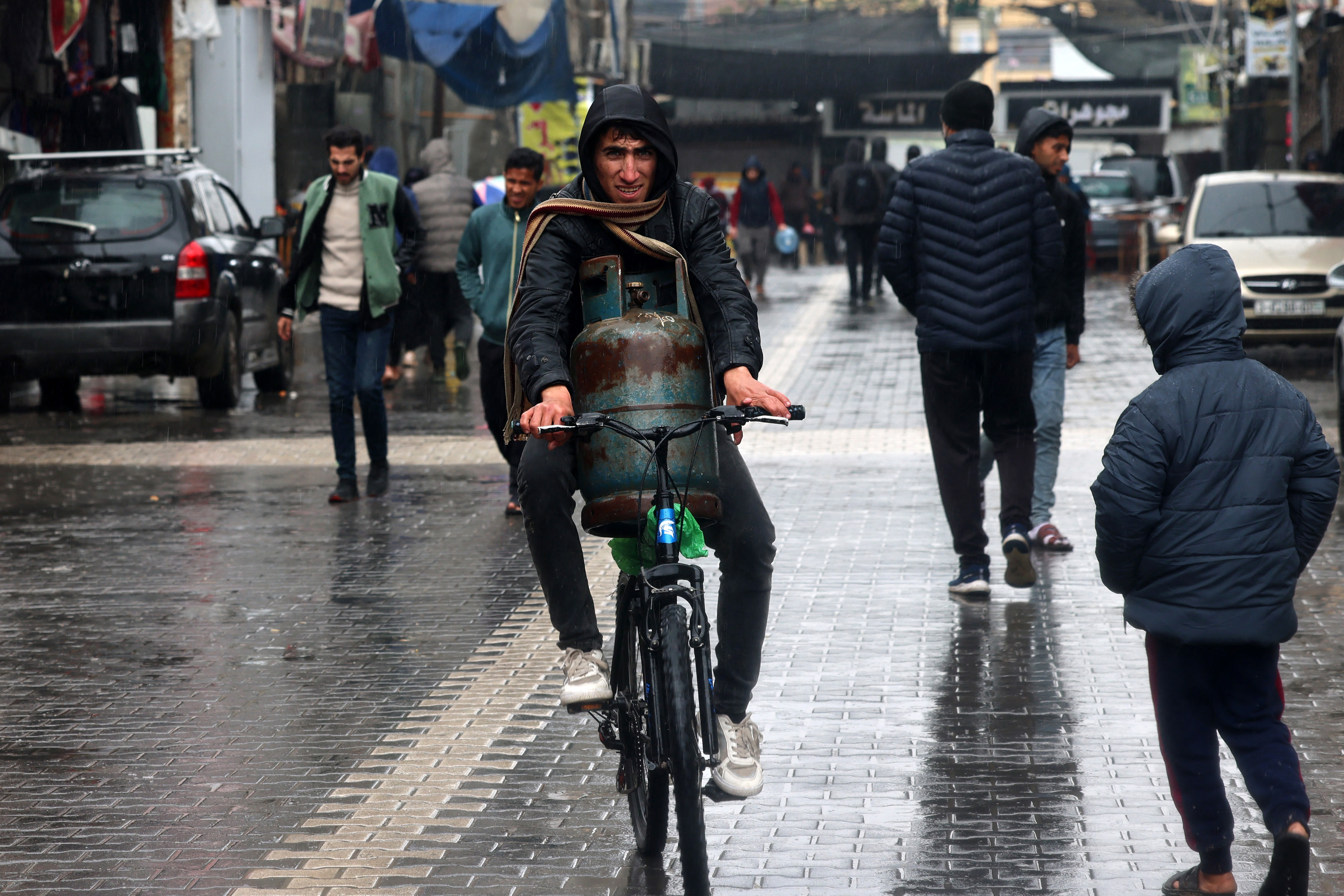A man transports a gas canister on a bicycle on a rainy day in Rafah in the southern Gaza Strip on January 27