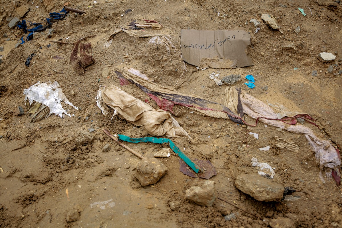 Shrouds containing human remains lie in the mud