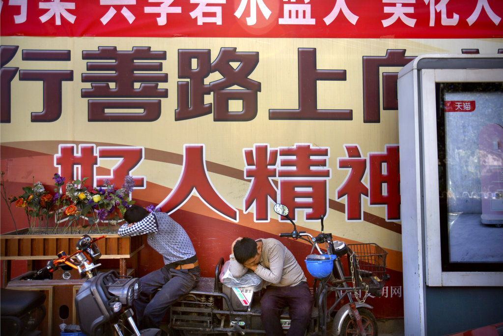 Construction workers take a nap in front of a billboard outside of a construction site in the central business district in Beijing, Friday, Sept. 22, 2017. China's Finance Ministry on Friday criticized the cut in the Standard &amp; Poor's rating agency's credit rating on Chinese government borrowing as a "wrong decision" and said it ignores the country's economic strength. (AP Photo/Mark Schiefelbein)