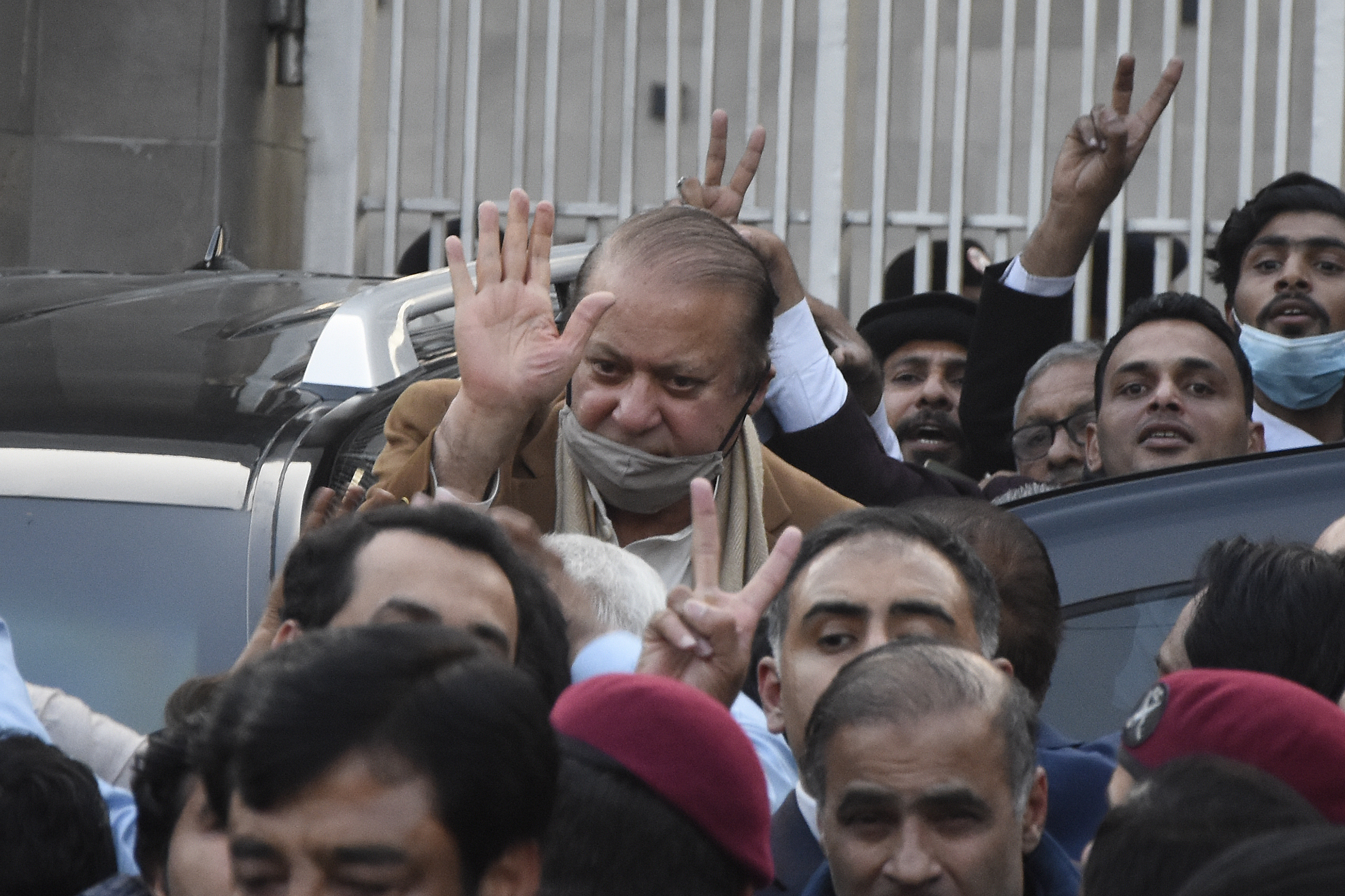 Pakistan's former Prime Minister Nawaz Sharif, center in brown coat, waves to his supporters as he leaves after a court hearing in Islamabad, Pakistan, Tuesday, Dec. 12, 2023. A Pakistani court on Tuesday overturned the 2018 conviction of former Prime Minister Sharif in a graft case and acquitted him, clearing his path to run in the parliamentary elections set to be held in February. (AP Photo/W.K. Yousufzai)