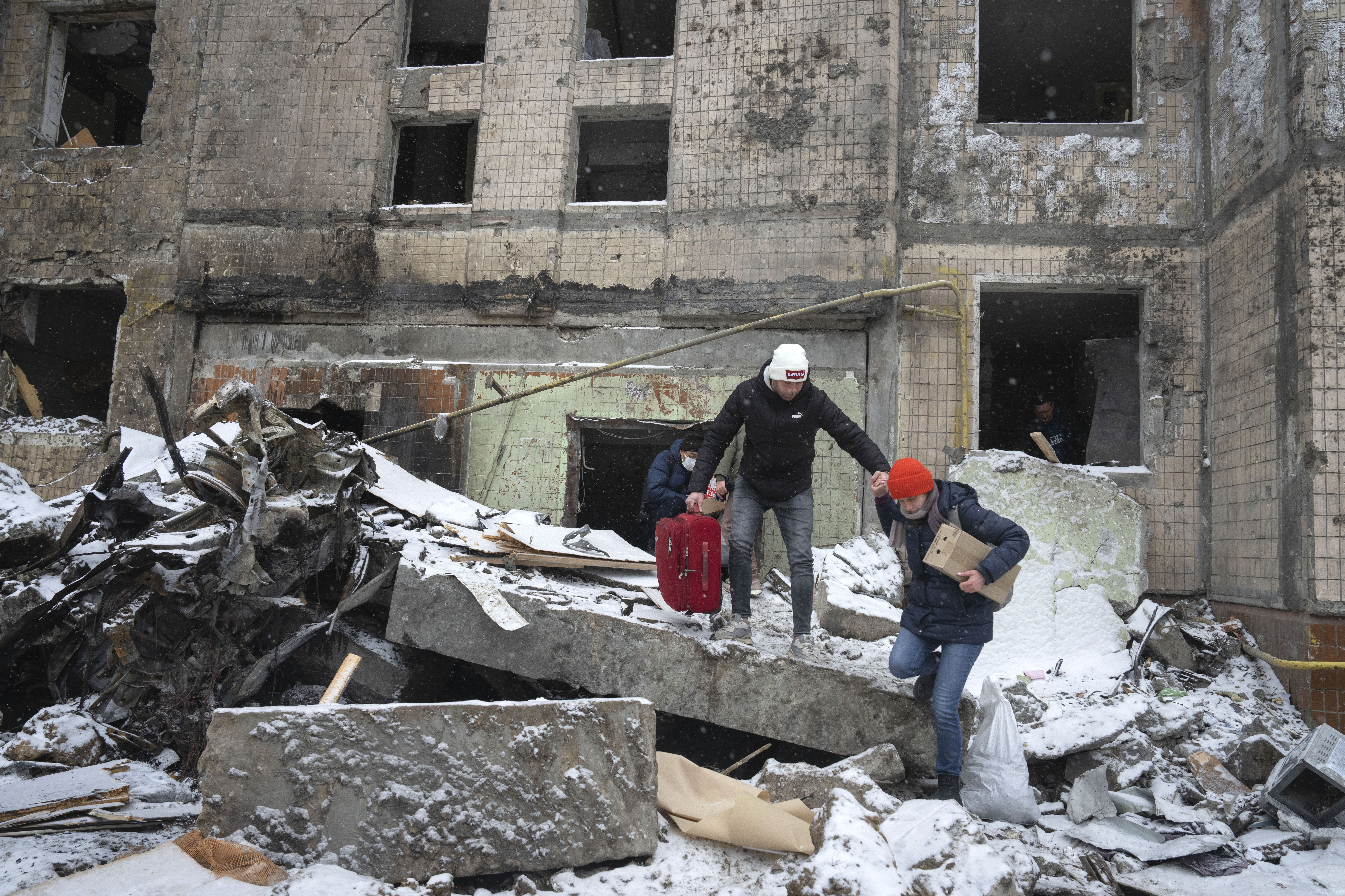 People walk with belongings from an apartment building destroyed after Tuesday's Russian attack, Kyiv, Ukraine, January 3, 2024
