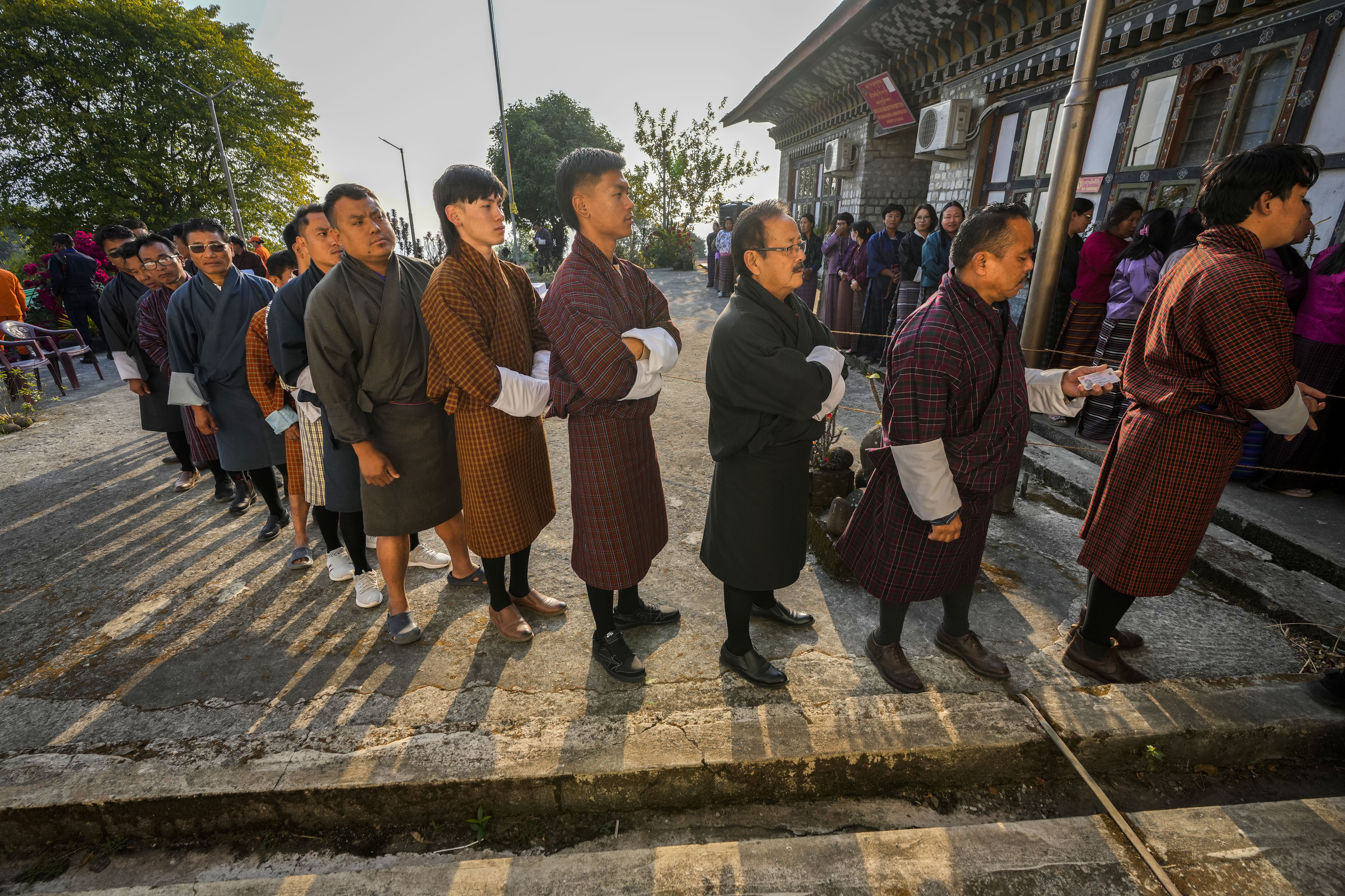 Bhutanese people in traditional attire queue up to cast their votes in the national elections in Deothang