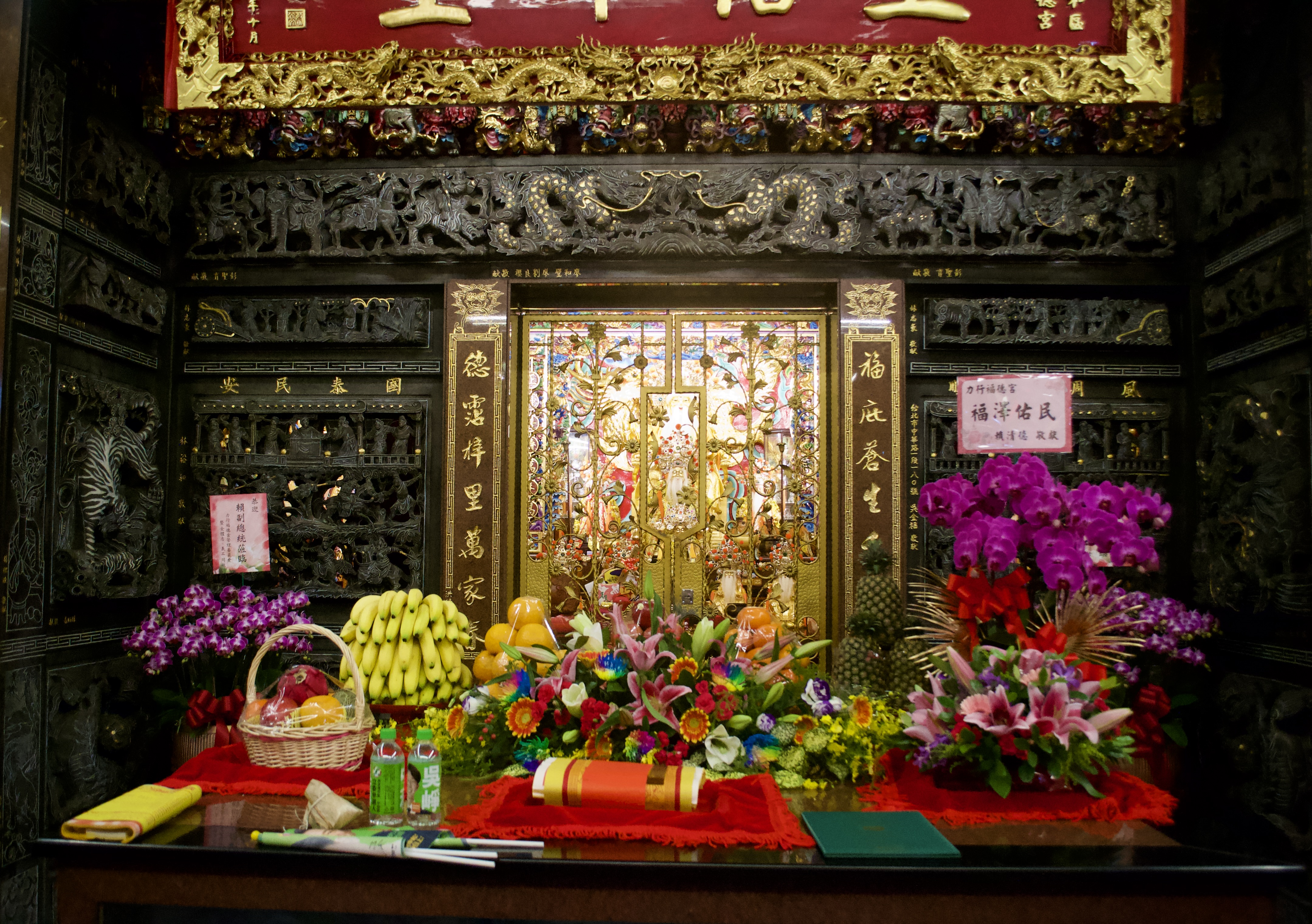 Offerings left on the altar at Lixing Fude temple. There are fresh fruit baskets, green flags and water bottles with Lai’s and Wu’s faces on them.