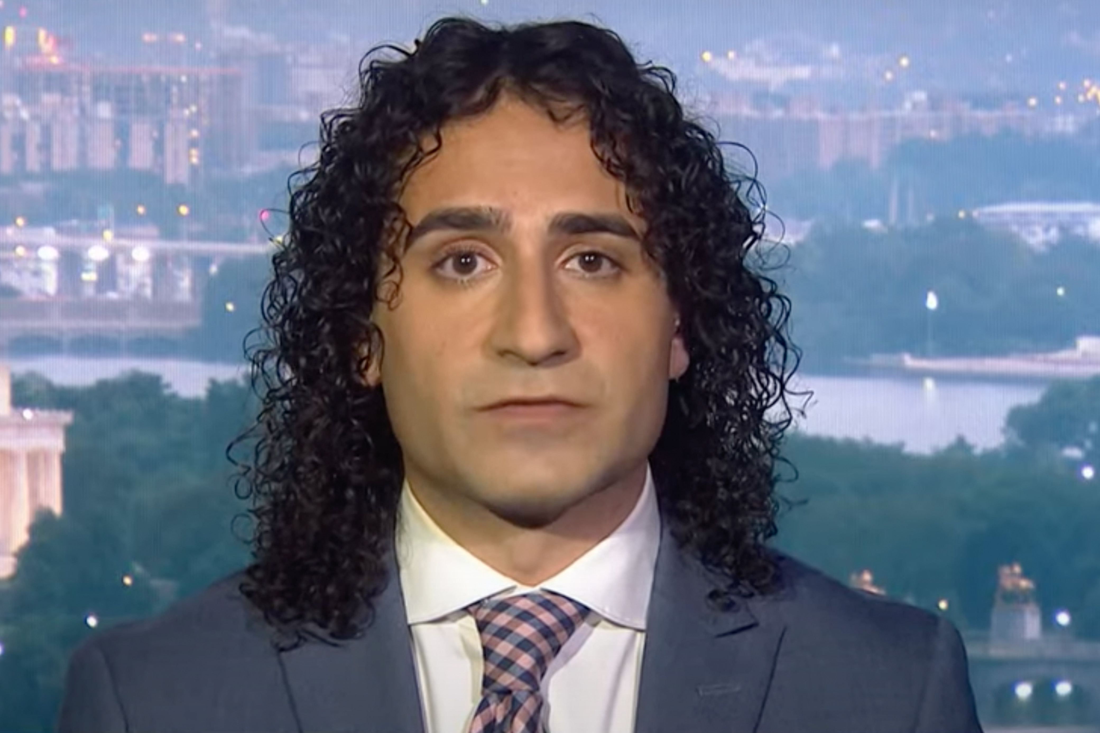 Tariq Habash, wearing a suit and tie, sits in a TV studio in Washington DC to give an interview.