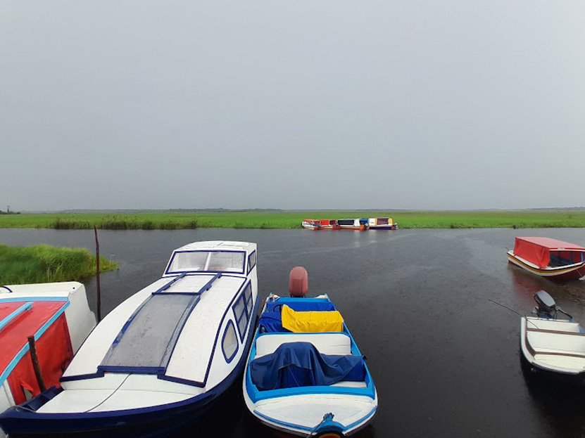 Small boats sit docked at Wakapoa, a disputed region of Guyana. Behind them, a river and marshland are visible.