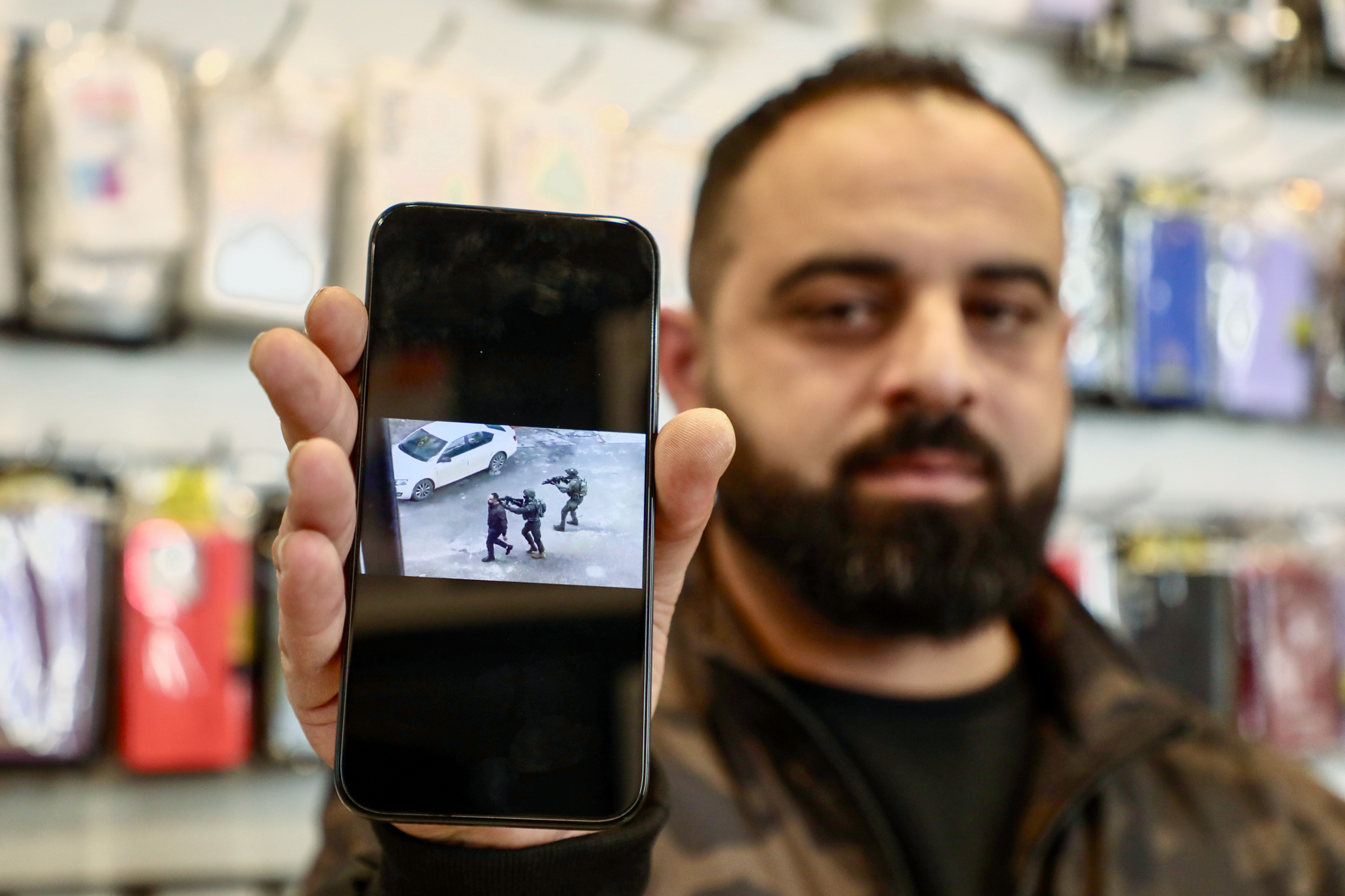 Bahaa el-Din holds a phone with a photo of him being used as a human shield
