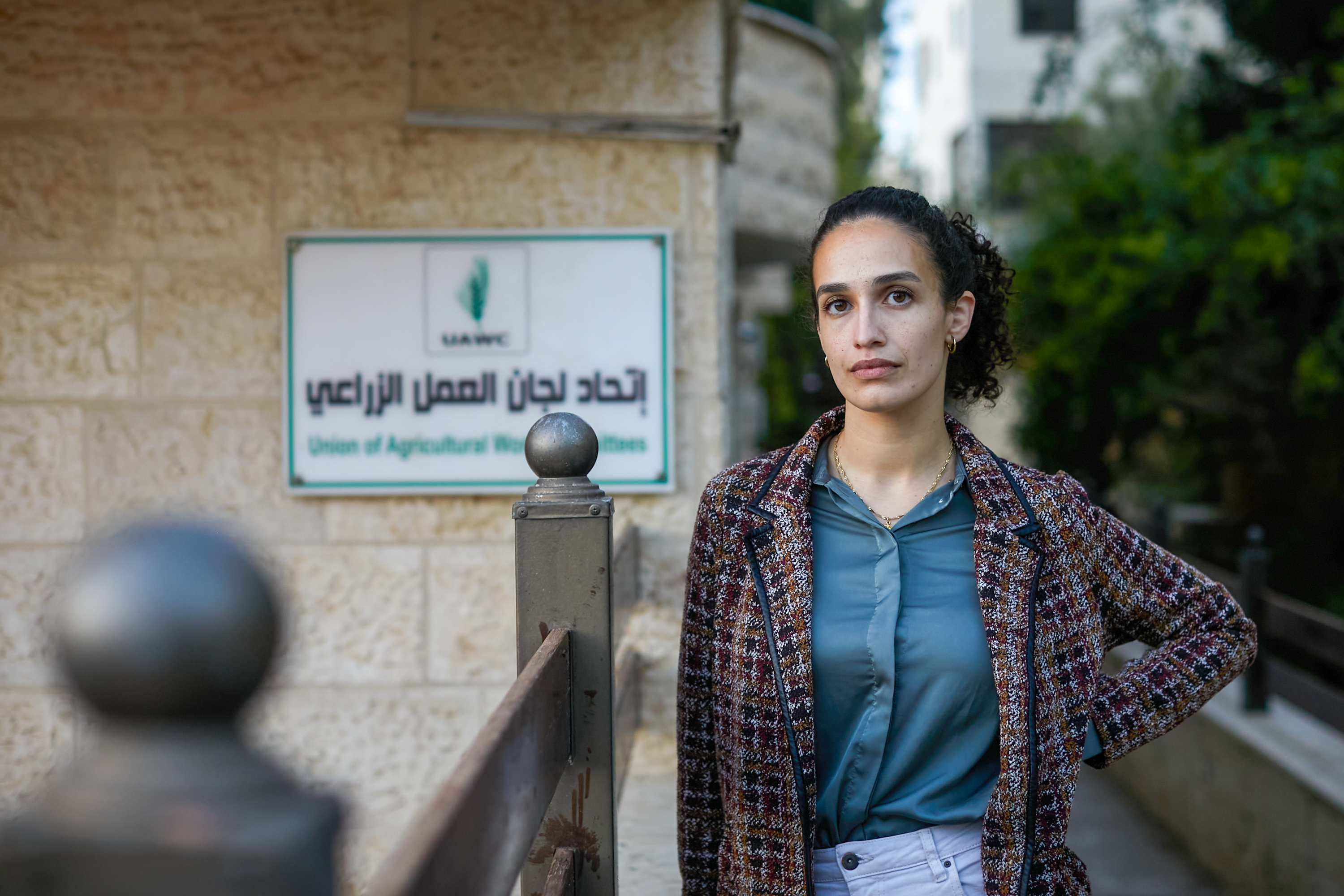 Yasmeen stands by the sign for the Union of Agricultural Work Committees