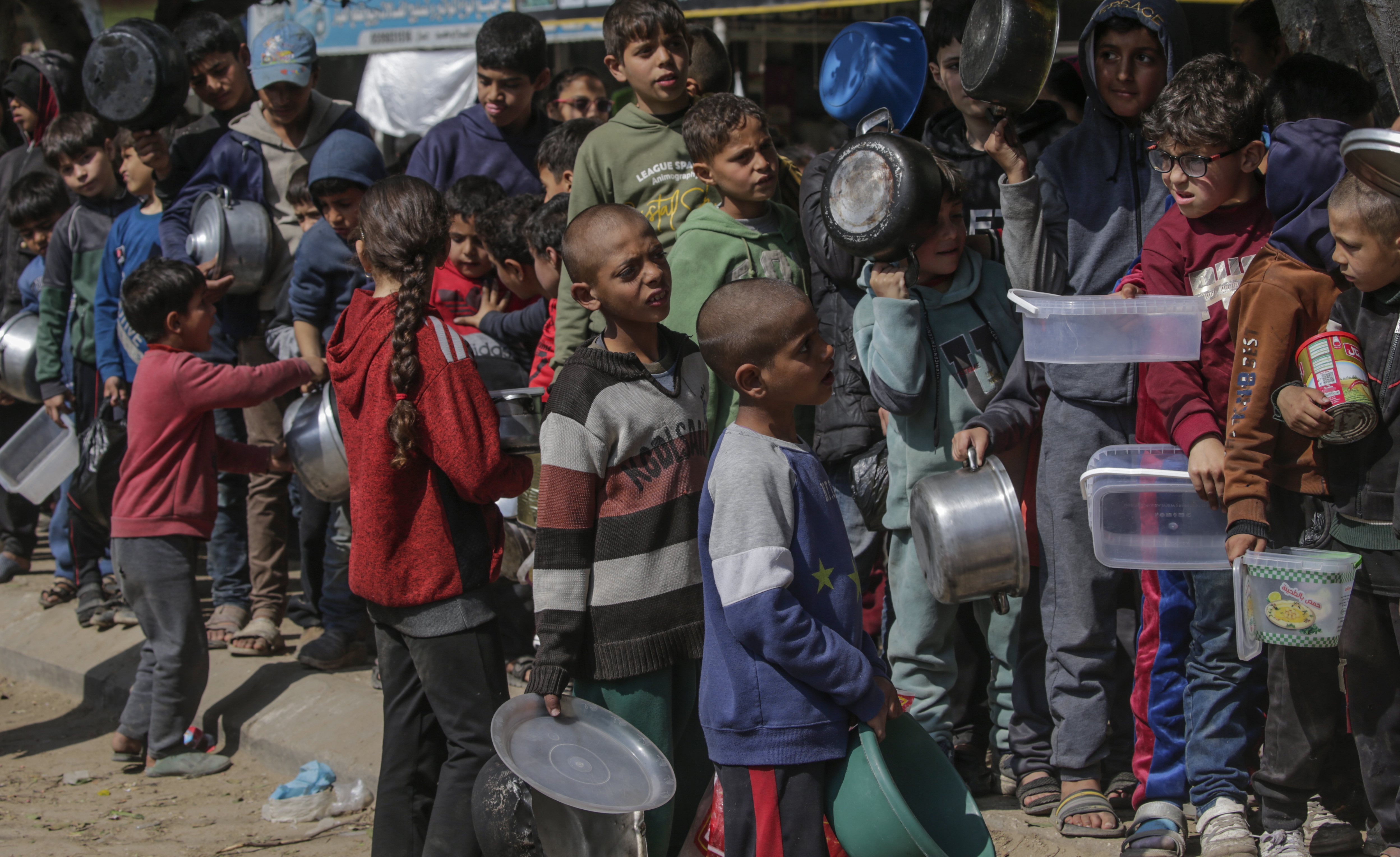Internally displaced Palestinian children queue up