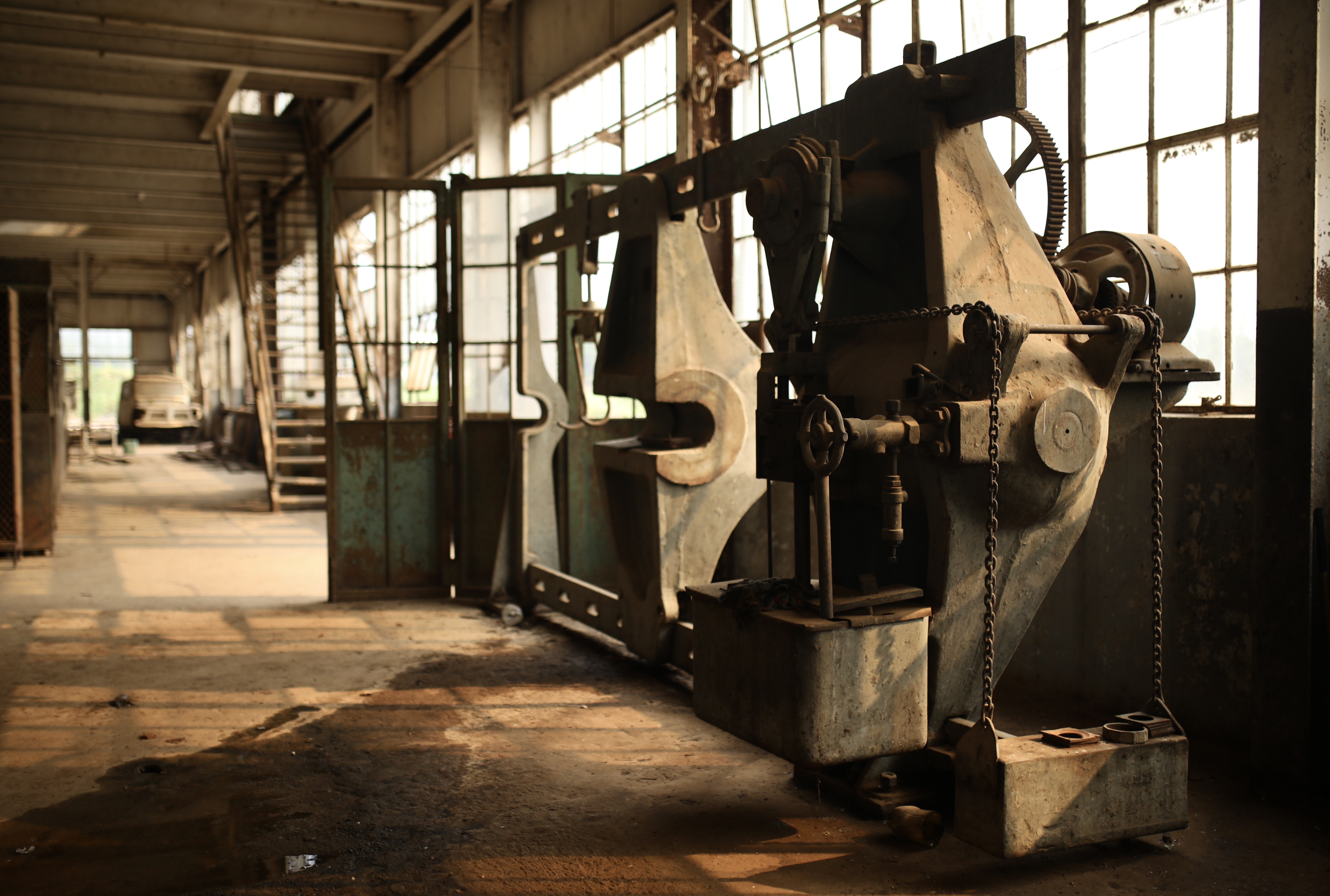 Heavy machinery sits rusted on an old factory floor.