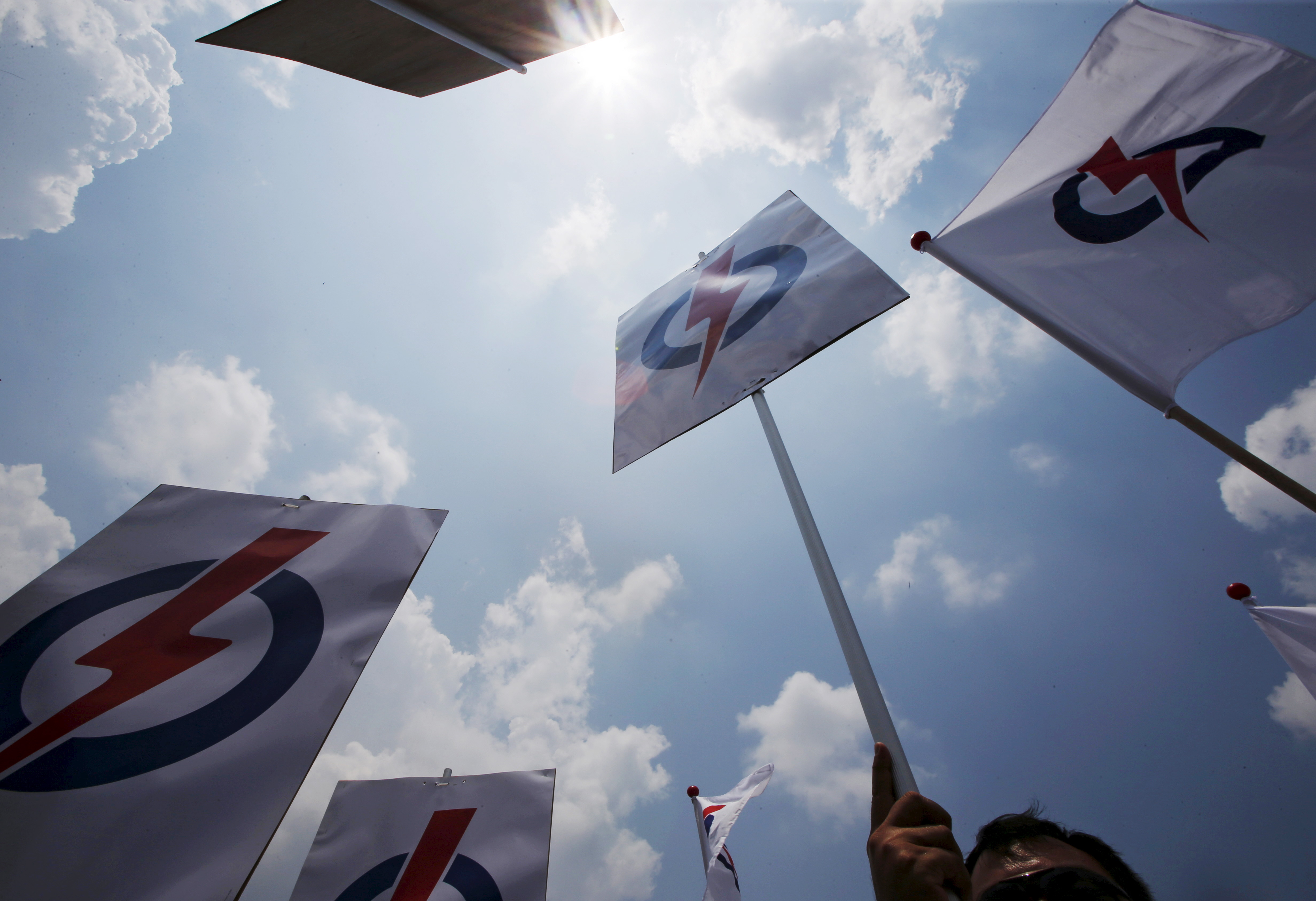 People holding PAP placards. The party's symbol is a red bolt through a blue circle.