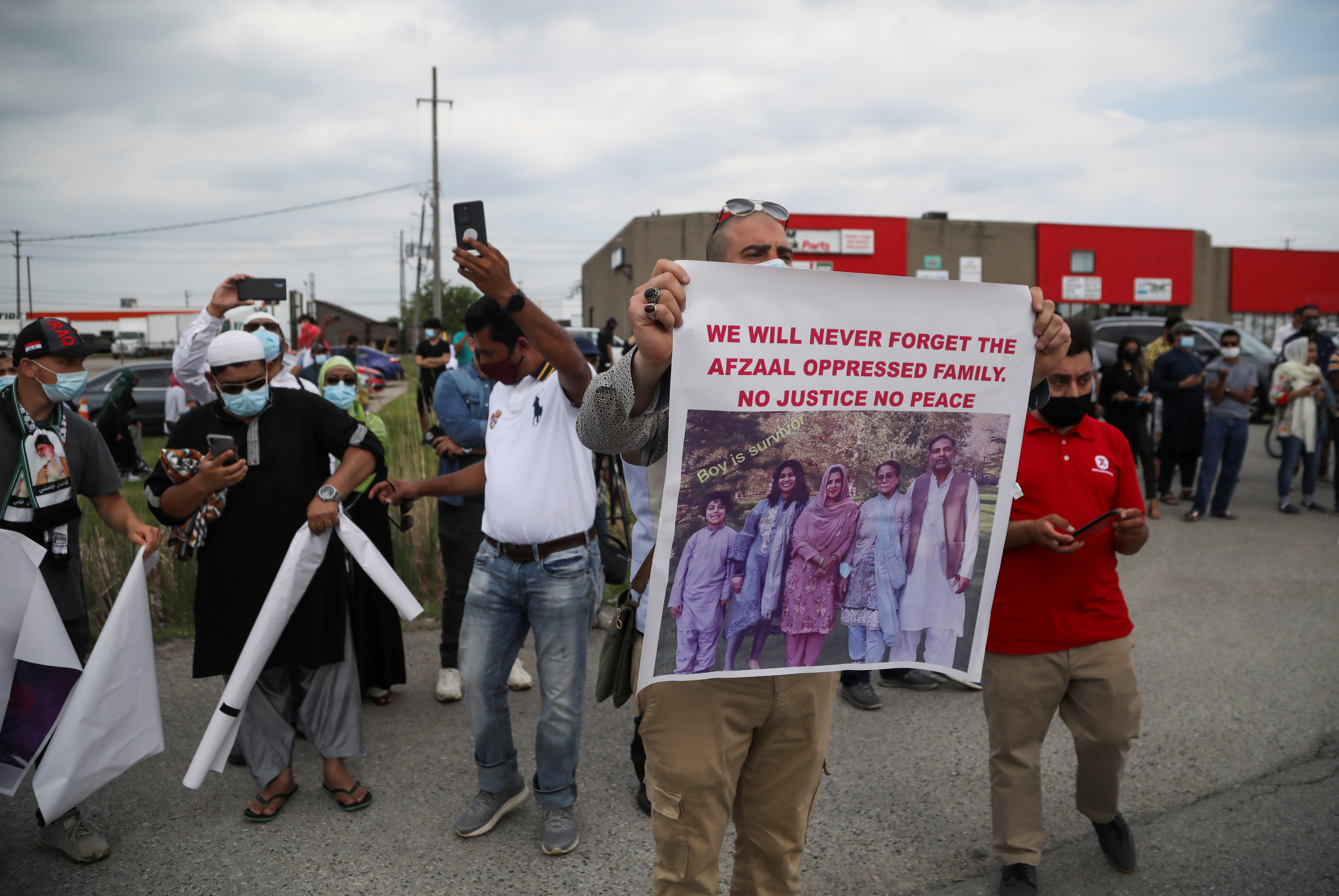 A man holds a banner after a funeral of the Afzaal family that was killed in what police describe as a hate-motivated attack, outside the Islamic Centre of Southwest Ontario, in London, Ontario, Canada