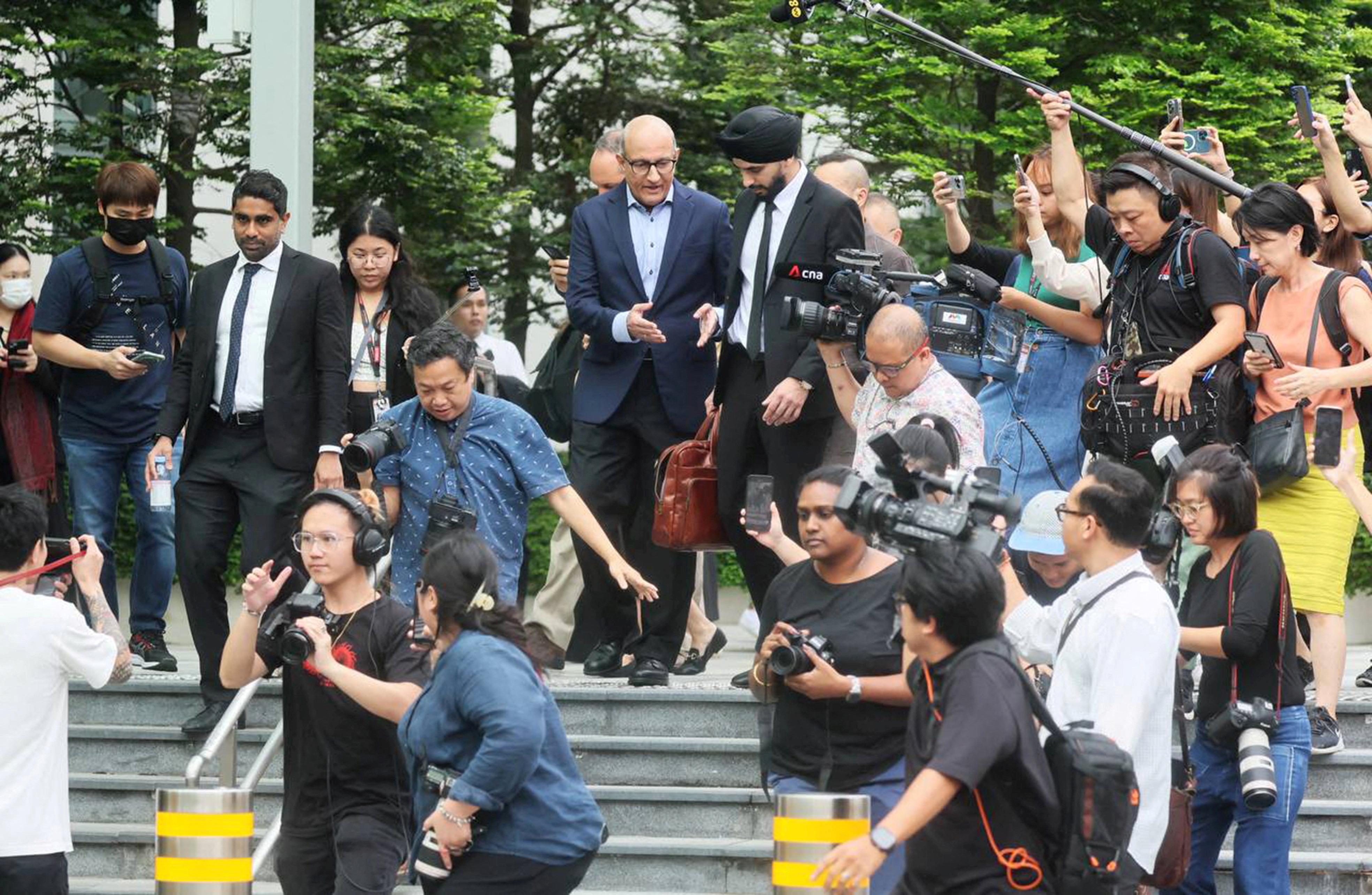 Singapore's former transport minister S Iswaran leaving court. He's surrounded by journalists.