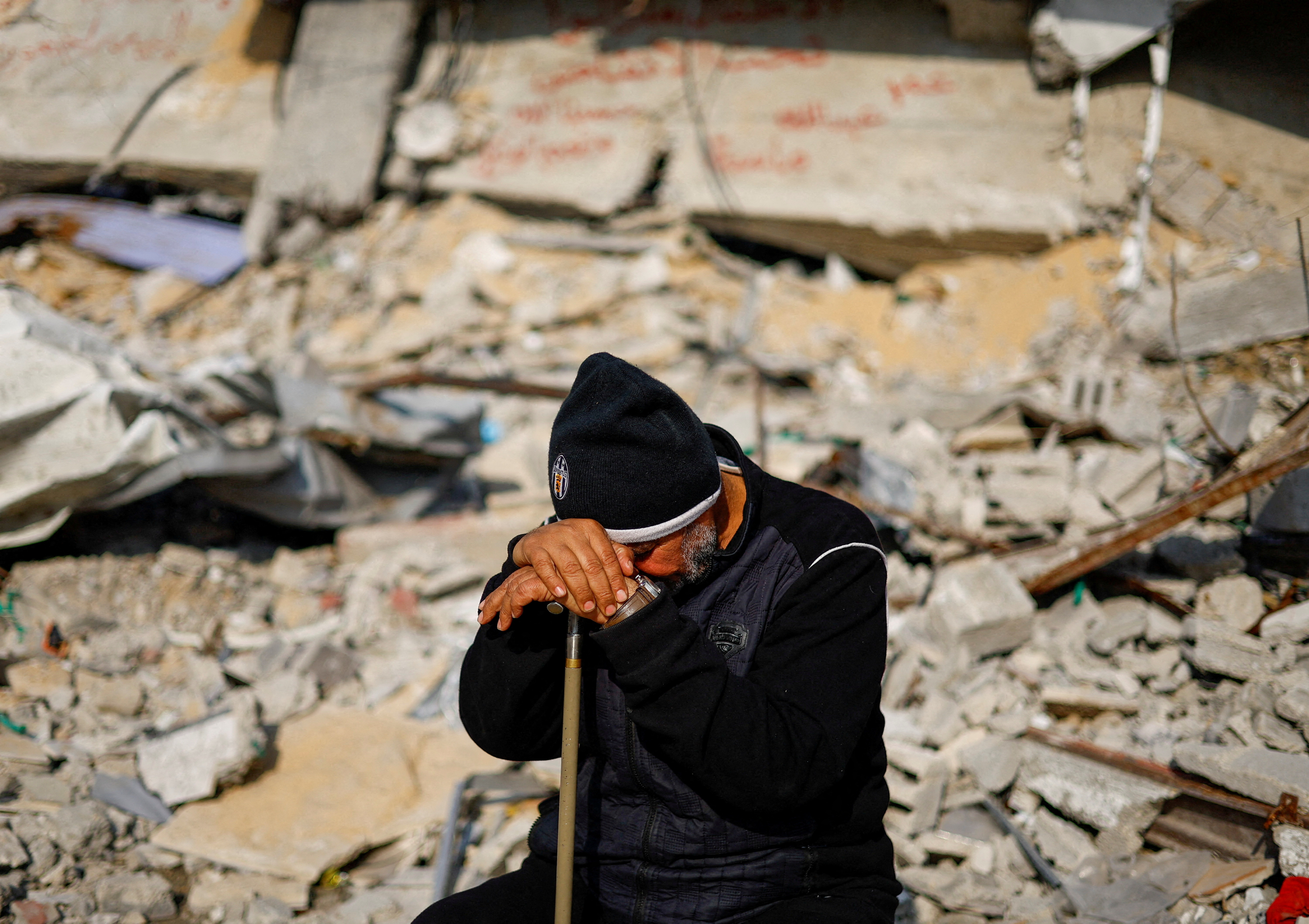 A Palestinian man leans his head against his cane amid the rubble of a destroyed building in Gaza