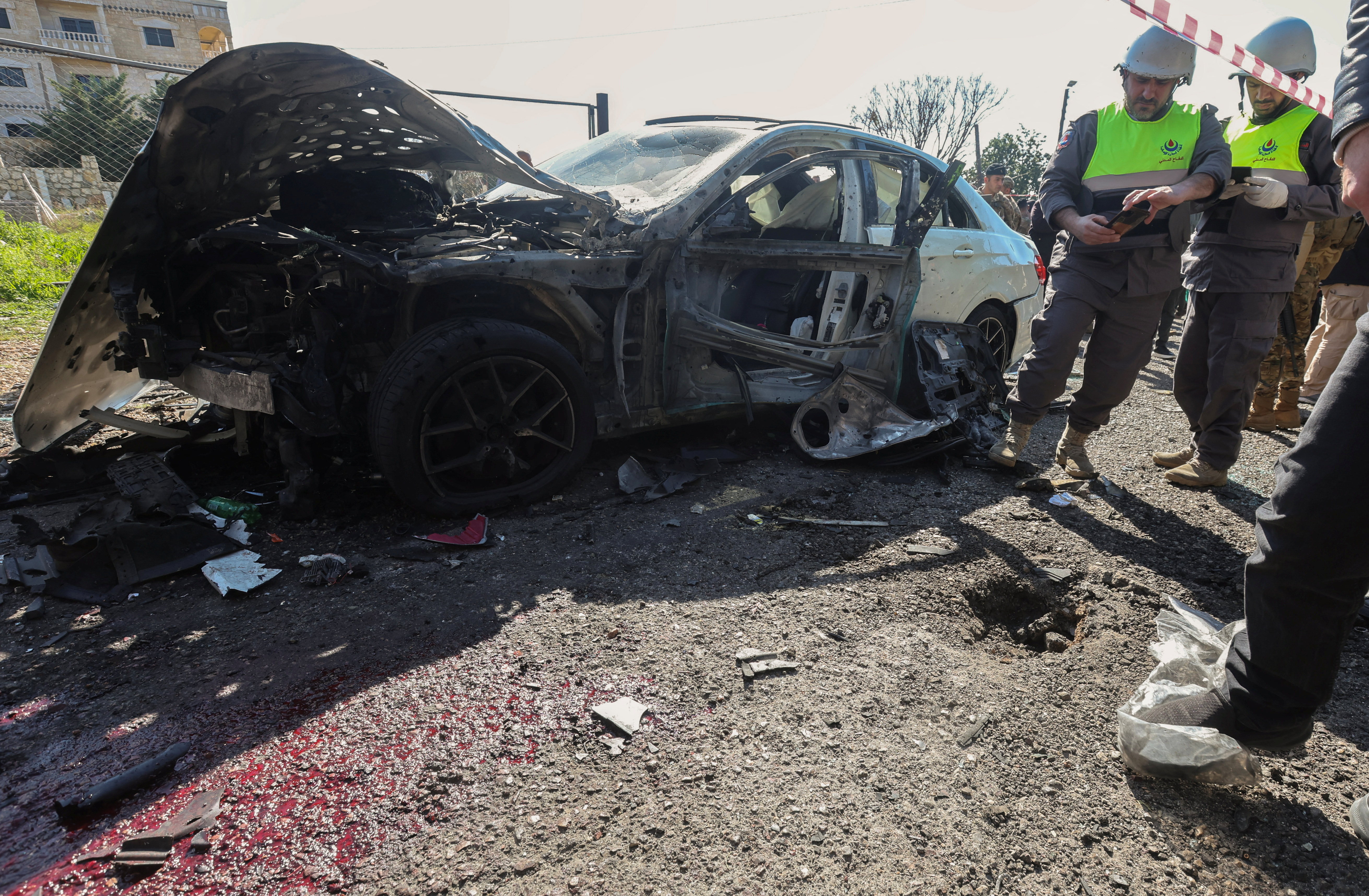 SENSITIVE MATERIAL. THIS IMAGE MAY OFFEND OR DISTURB Members of the Civil Defence inspect the area next to a destroyed vehicle in the aftermath of what security sources said was an Israeli strike, in Jadra, Lebanon February 10, 2024. REUTERS/Aziz Taher