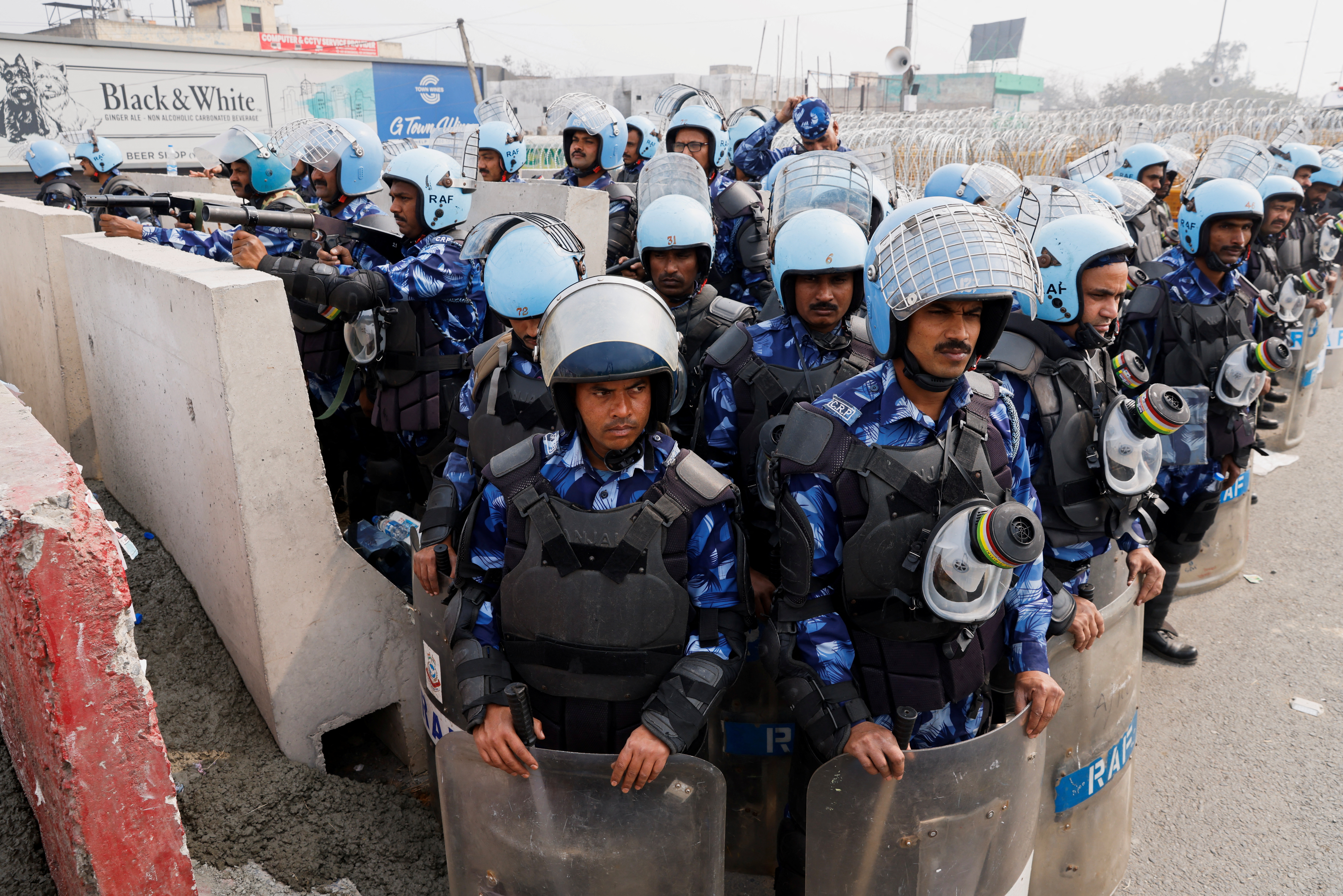Police officers stand guards as barricades are erected on a national highway to stop farmers