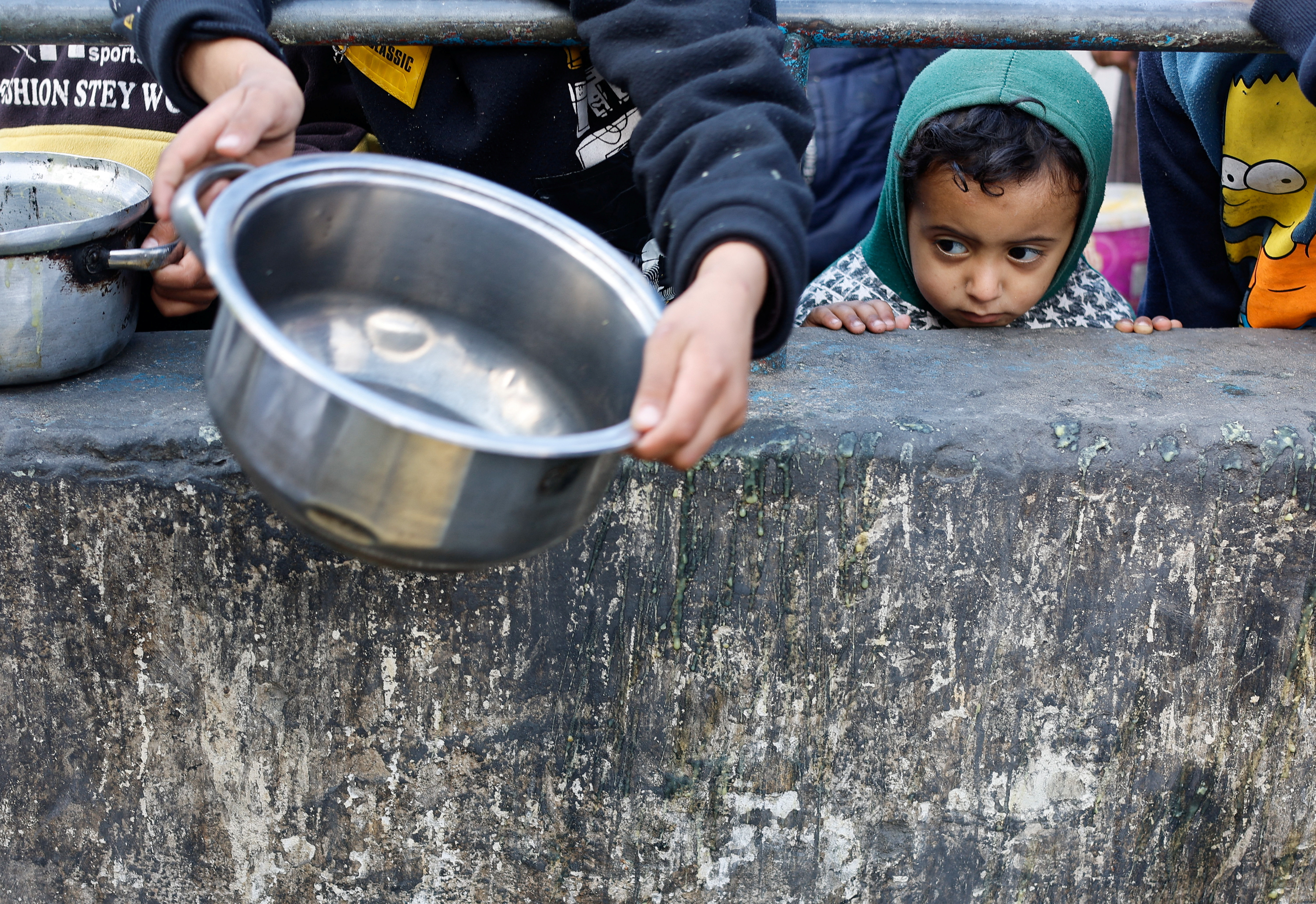 A Palestinian child looks on while waiting to receive food