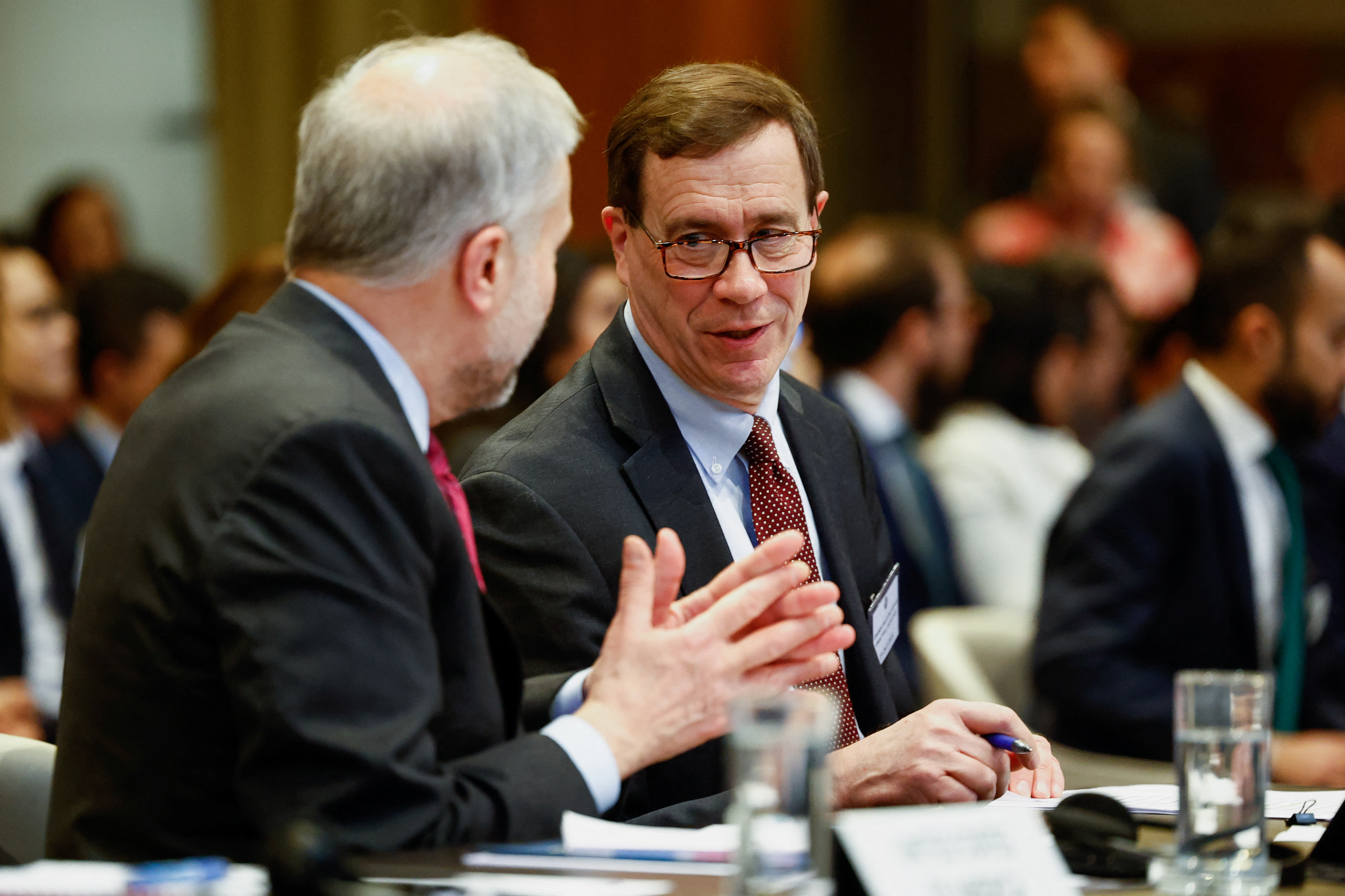 a man in a red tie speaks to a colleague