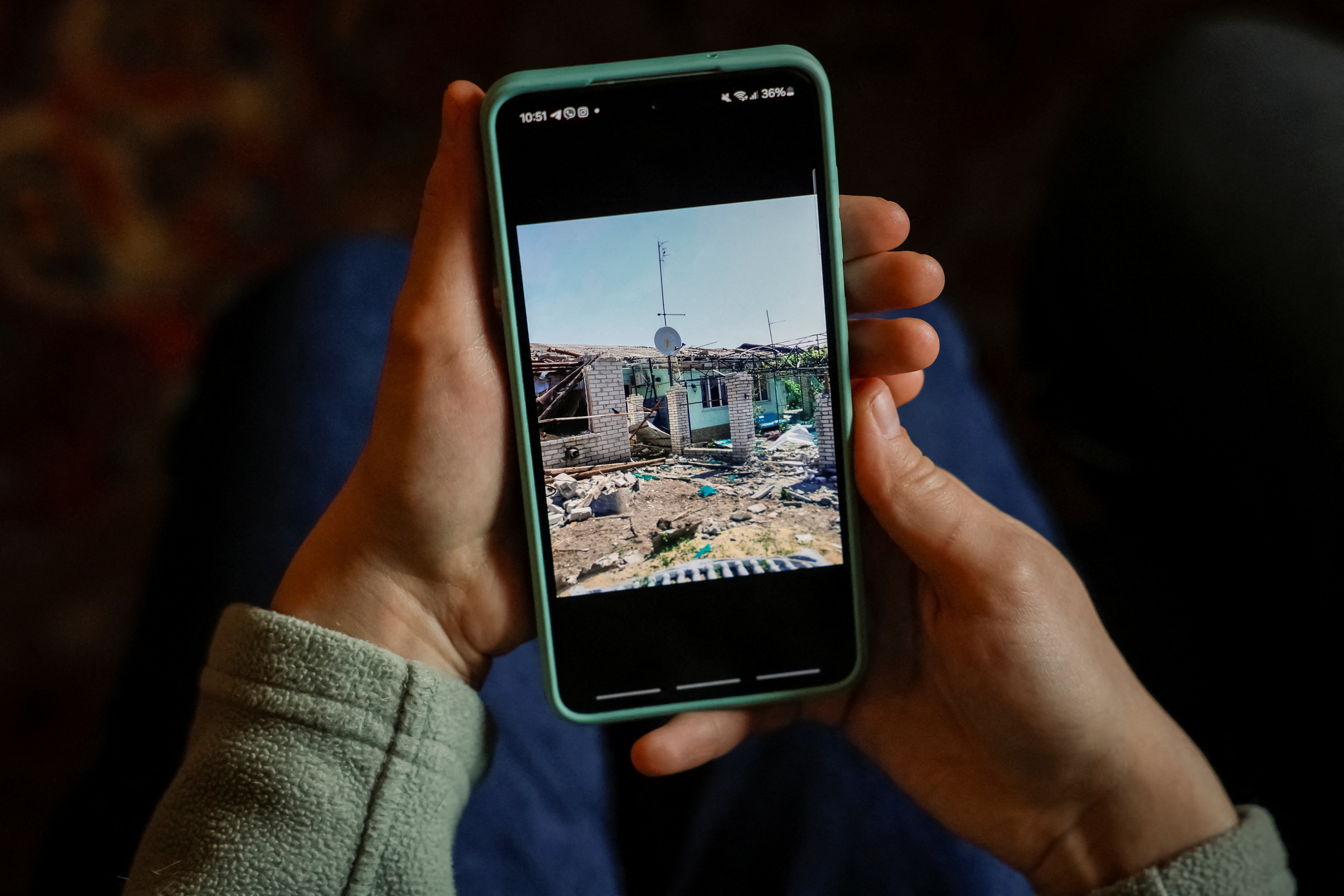 Anastasiia Korobchenko, 23, an internally displaced person (IDP) shows a picture of her destroyed house occupied by Russian troops in Rubizhne in Luhansk region