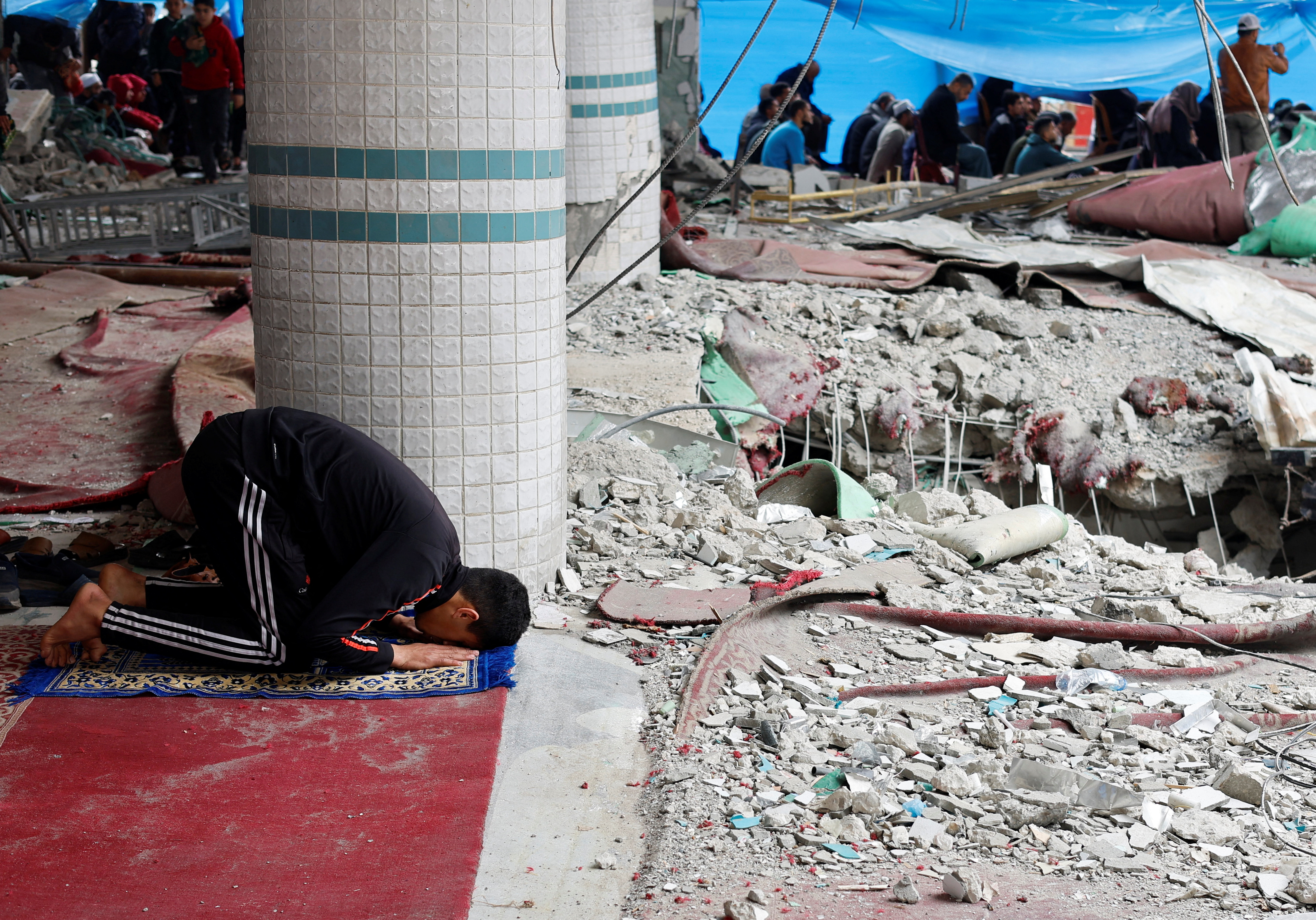 A Palestinian man performs Friday prayers at the ruins of a mosque destroyed in Israeli strikes, amid the ongoing conflict between Israel and Hamas, in Rafah in the southern Gaza Strip February 23, 2024. REUTERS/Mohammed Salem