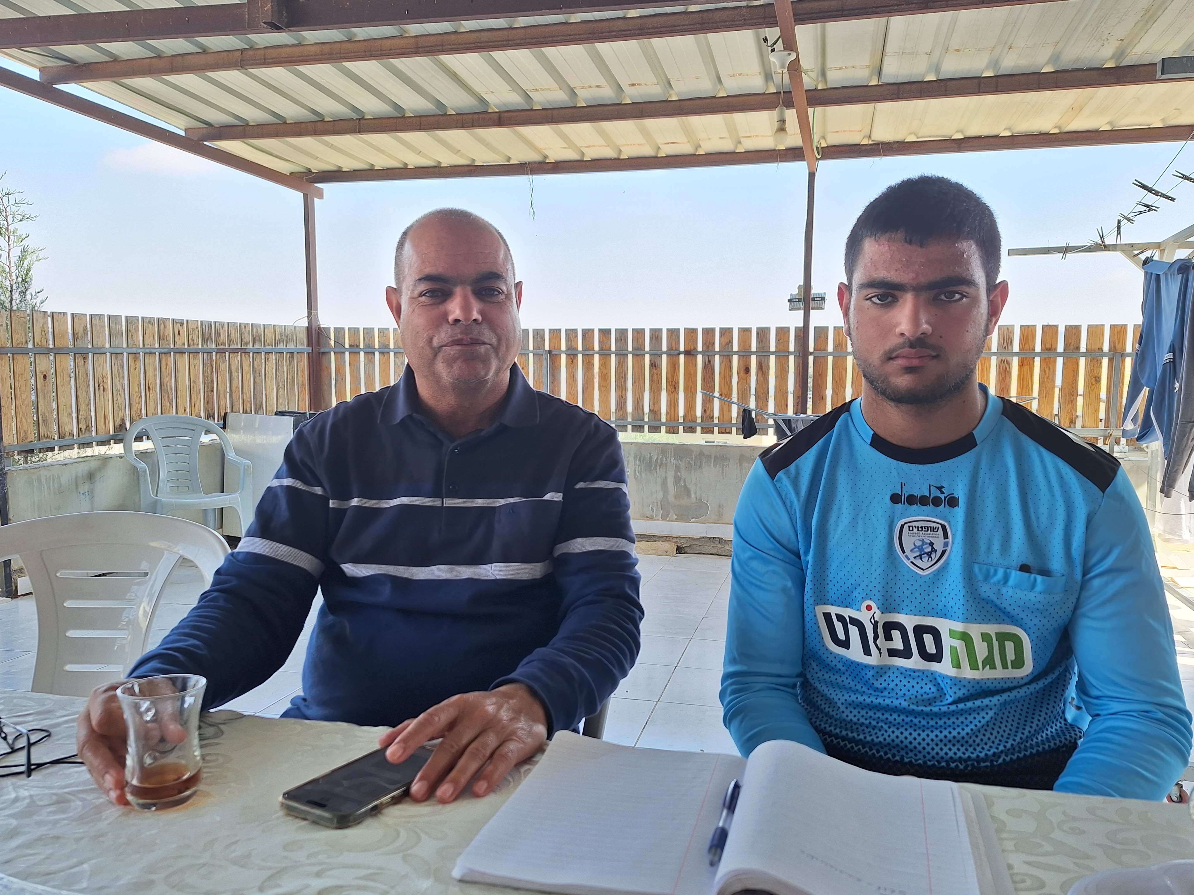 Khalil al-Amour sits next to his son Mohamed in their unrecognised village Khan al-Sira. [Mat Nashed/Al Jazeera]